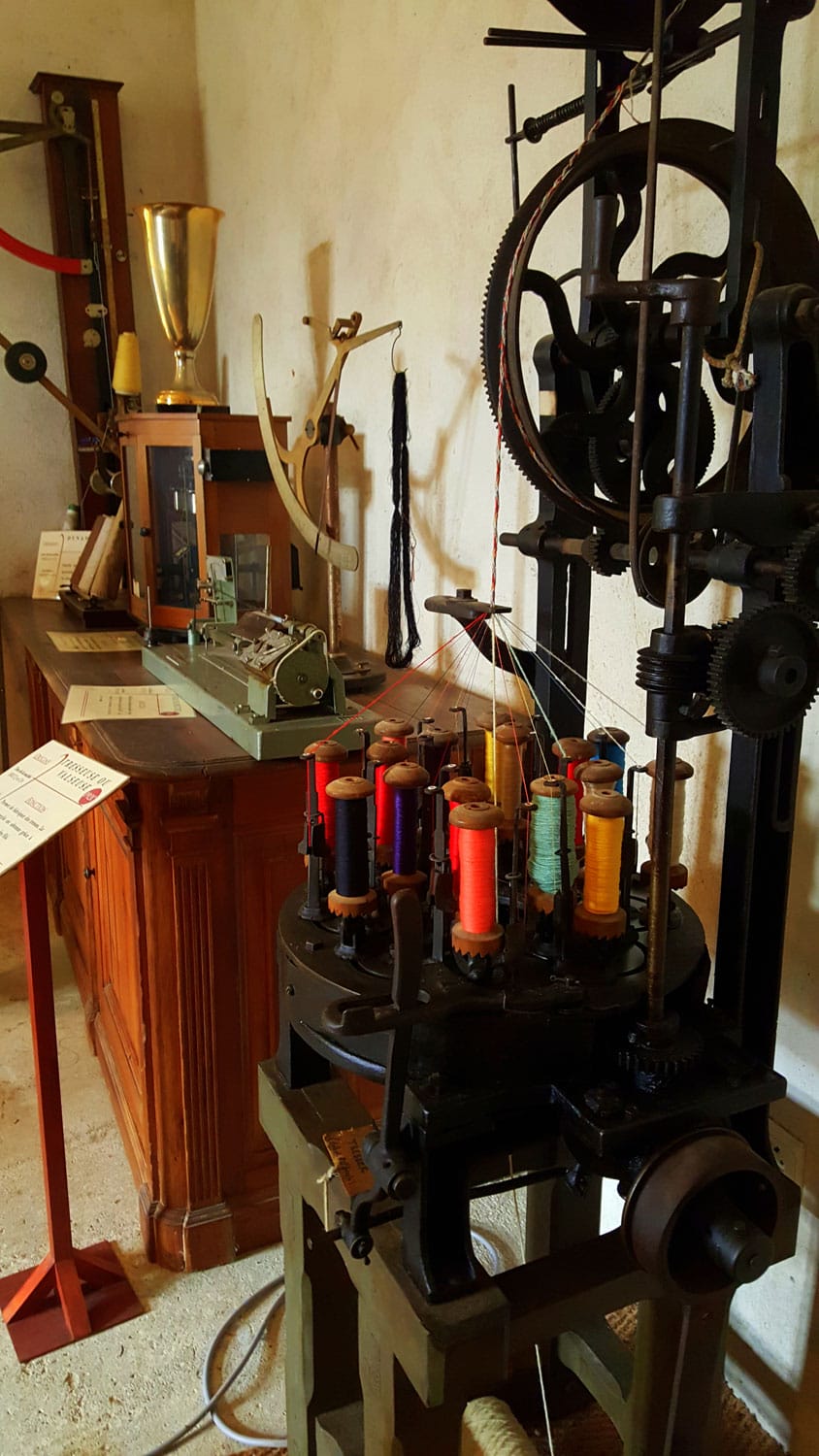 Machine à filer ancienne avec ses bobines colorées au musée du tisserand de Varaignes, patrimoine artisanal du Périgord Vert