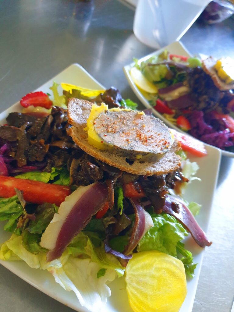L'Assiette Périgord du Château : une salade gourmande composée de gésiers confits, de tranches de magret séché et d'une belle tranche de foie gras mi-cuit sur un toast croustillant, parsemée de pointes de piment d'Espelette.