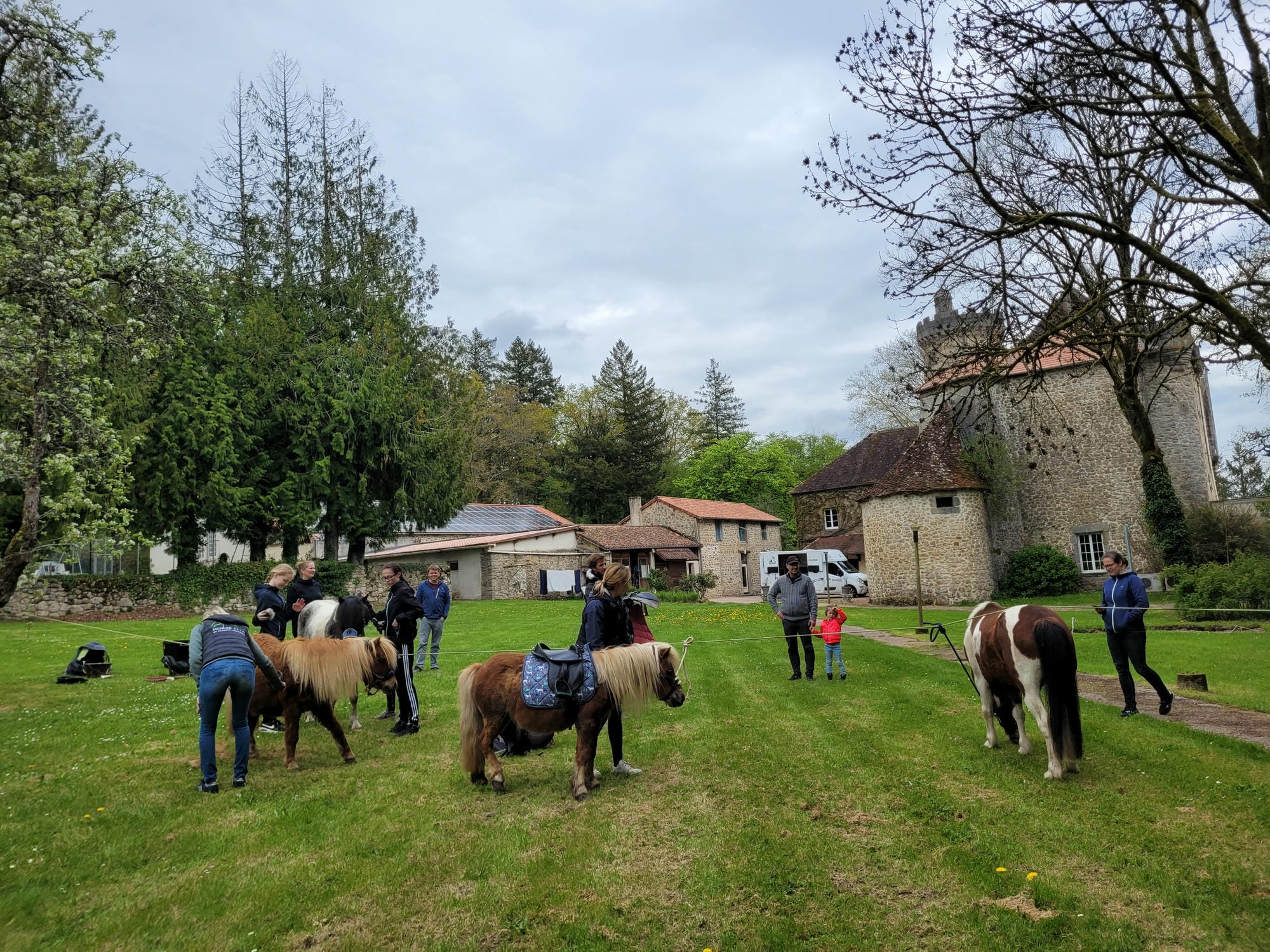 Plusieurs personnes à cheval sur la prairie, face au château, équitation au Camping Le Verdoyer