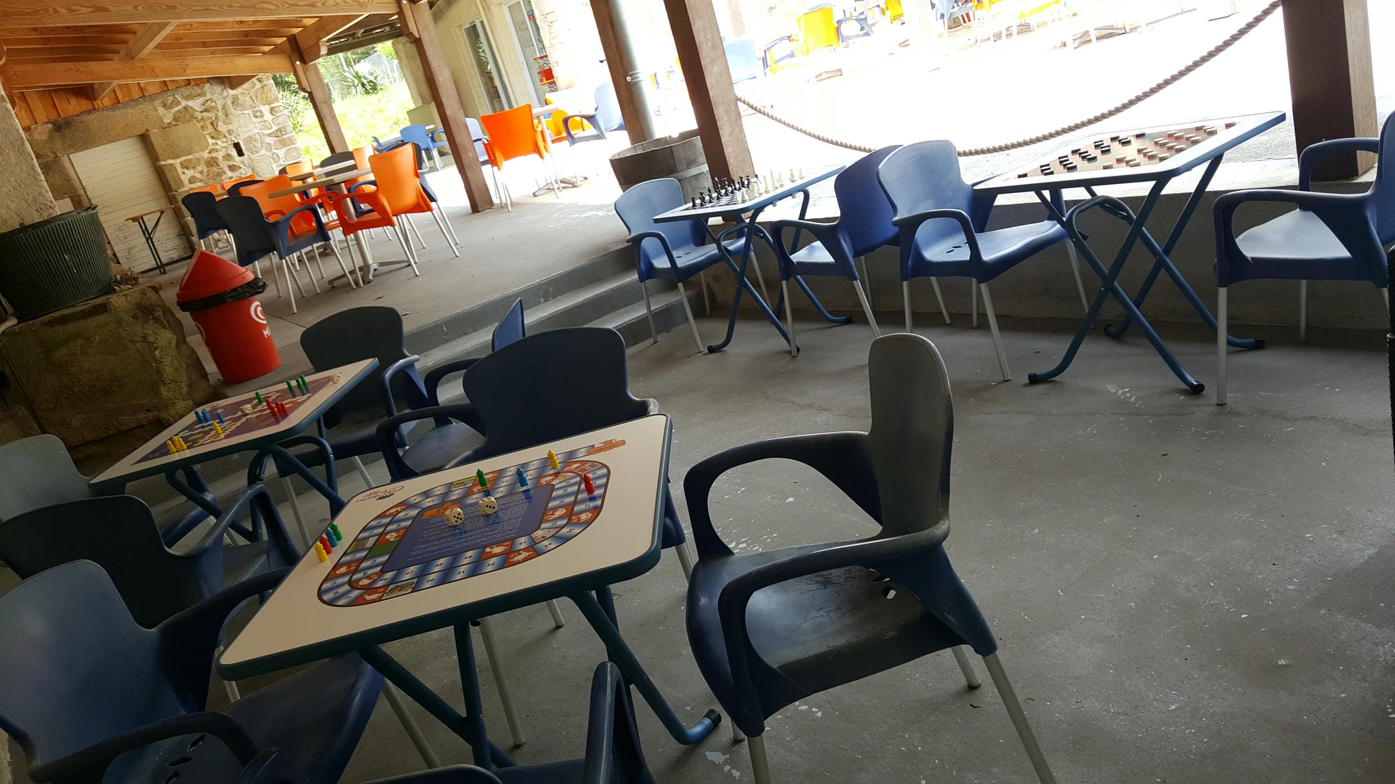 Tables et chaises dans une salle, prêtes pour des jeux de société au Camping Le Verdoyer (borne incendie visible)