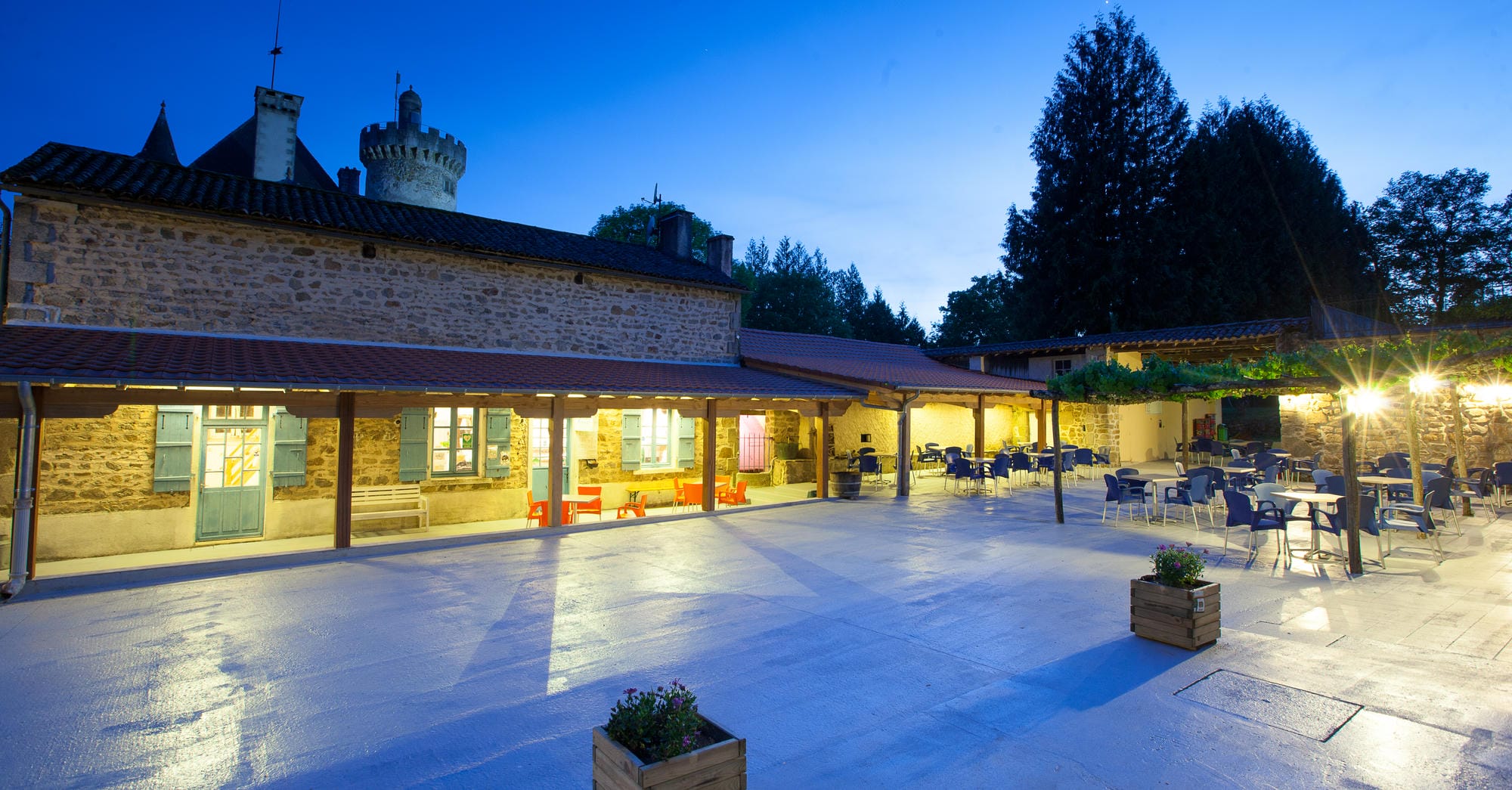 Terrasse du bar éclairée en soirée avec vue sur le Château le Verdoyer en Dordogne