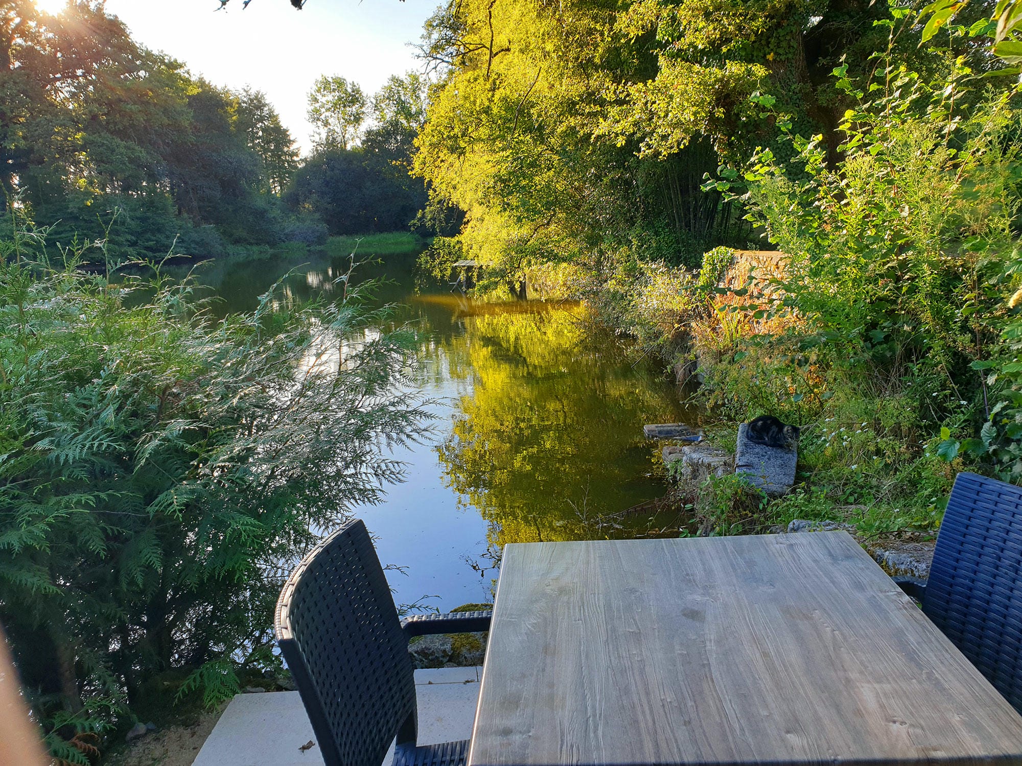 Table et chaises installées au bord de l'étang de pêche du Château le Verdoyer, lieu de pique-nique