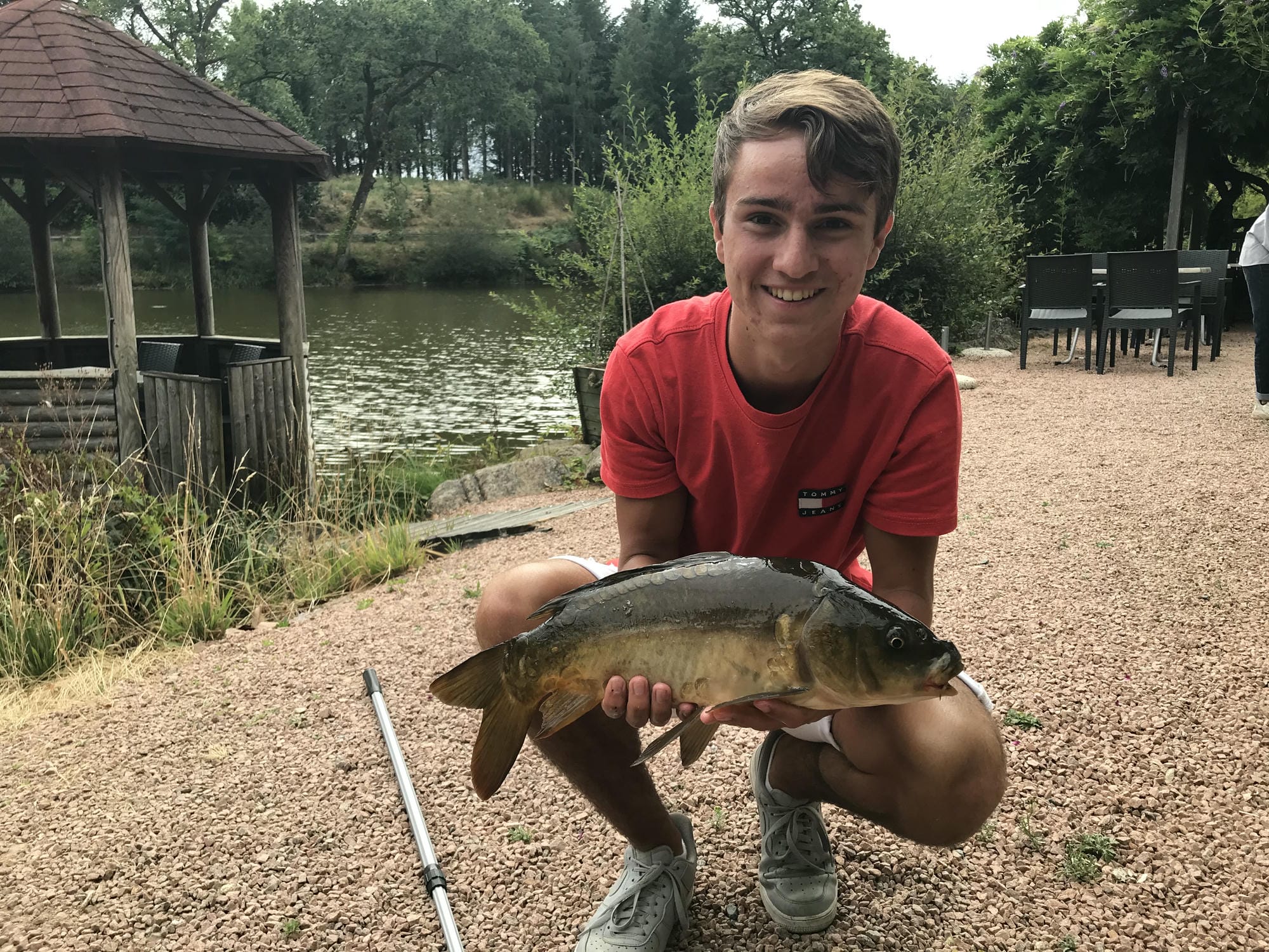 Garçon agenouillé tenant un poisson sur la berge, pêche à l'étang du Verdoyer