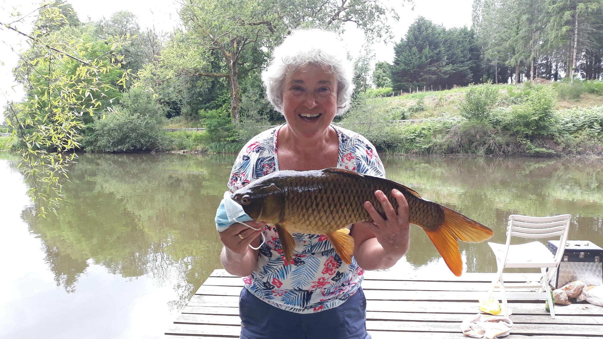 Femme tenant un poisson sur le ponton de l'étang de pêche du Château le Verdoyer