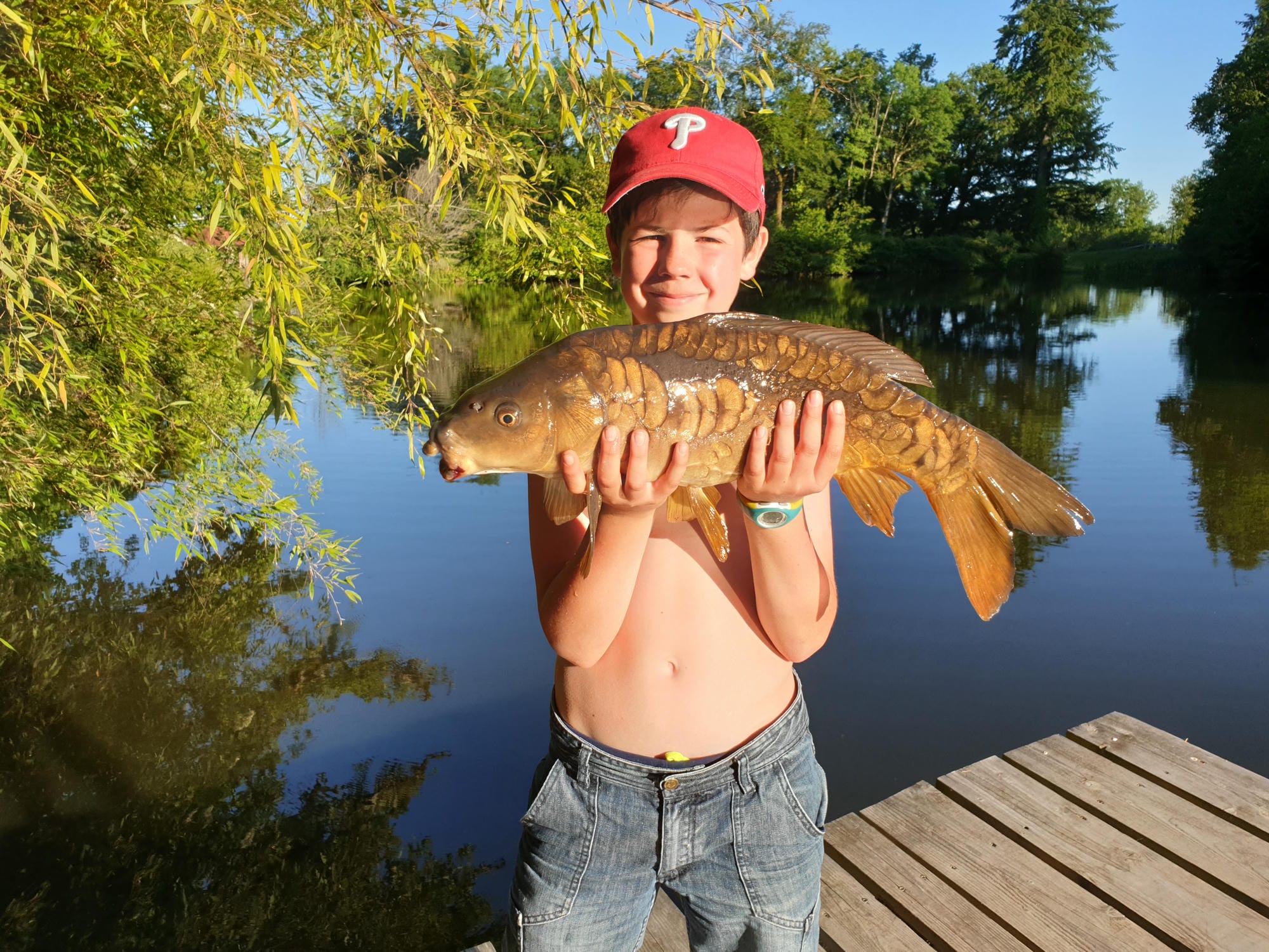 Beau poisson sur un ponton avec un jeune garçon le tenant, pêche au Château le Verdoyer