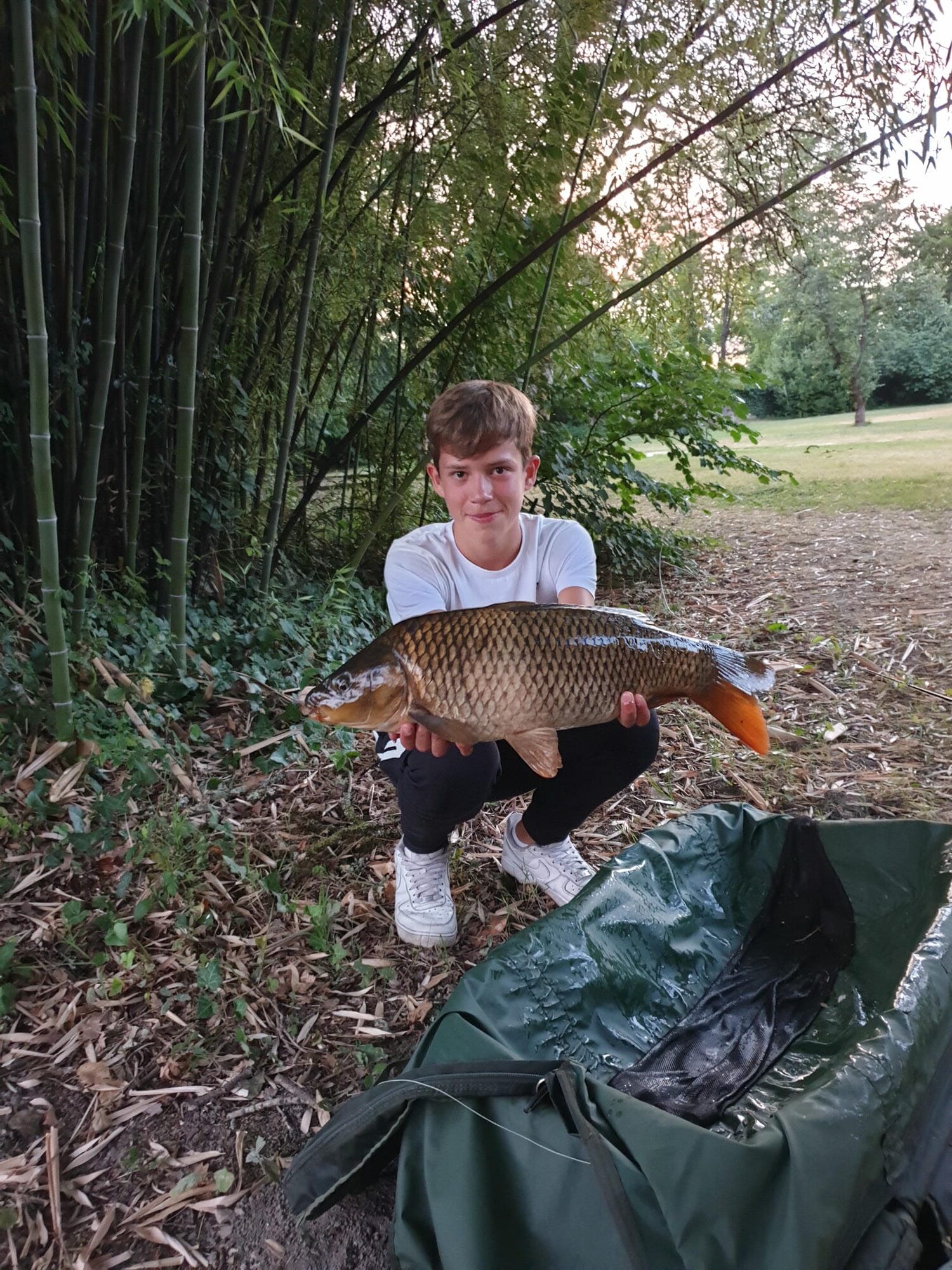 Gros poisson pêché dans l'étang du Verdoyer, pêcheur agenouillé à côté