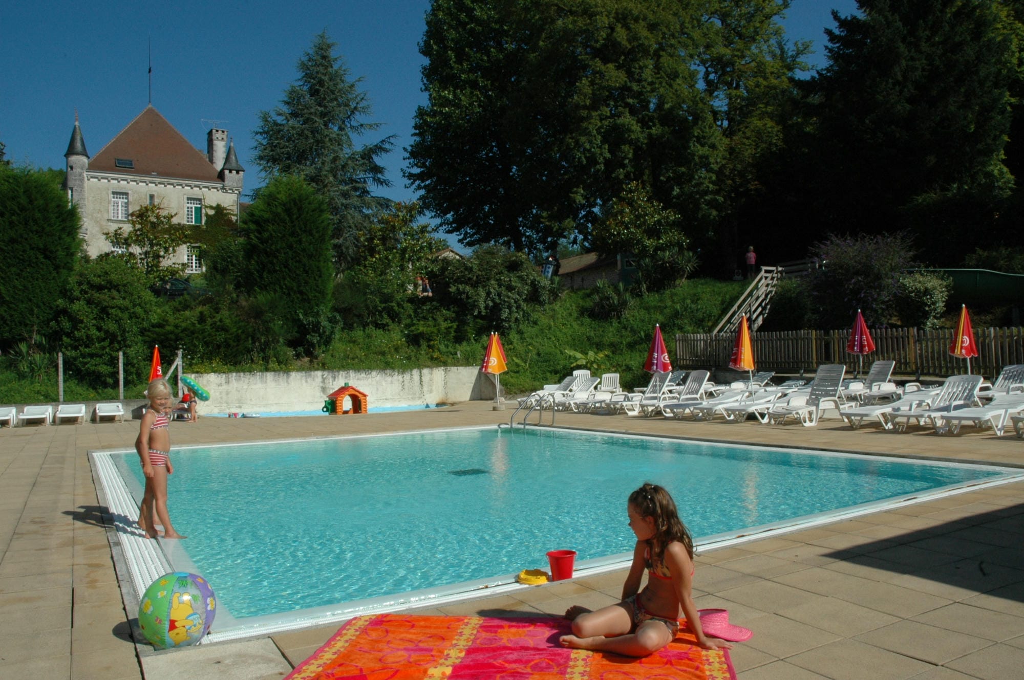 Enfants assis sur une serviette au bord de la piscine du Camping Château le Verdoyer