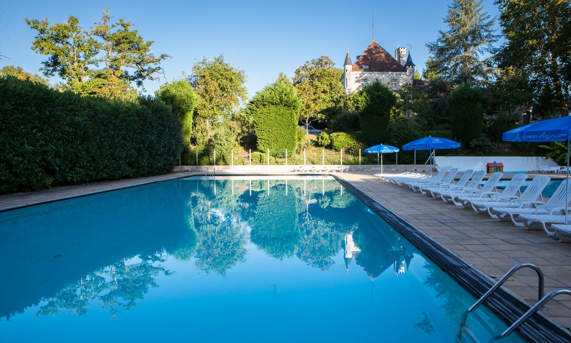 Piscine extérieure avec transats et parasols au Camping Château le Verdoyer, Dordogne