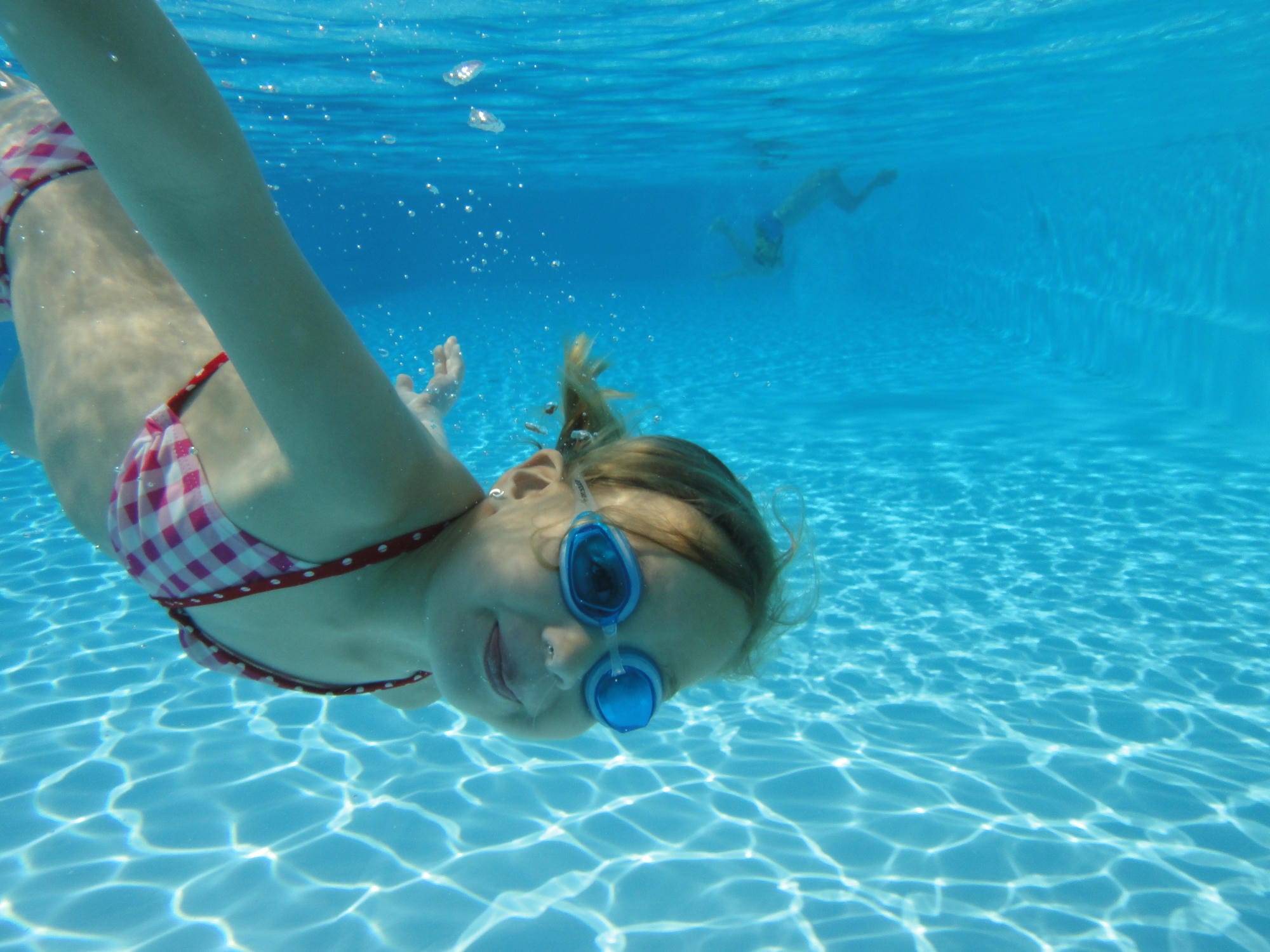 Enfant sous l'eau avec lunettes de natation nageant dans la piscine du Château le Verdoyer