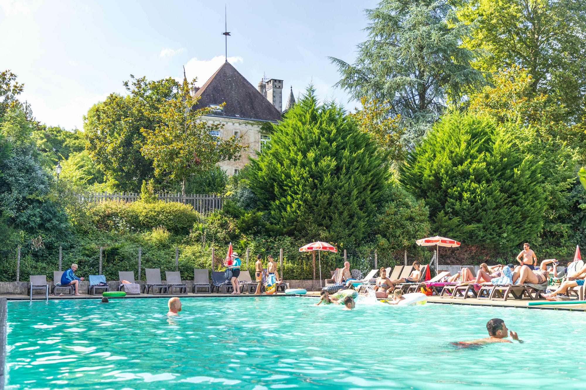 Grande piscine extérieure avec nageurs, parasols et transats au Camping Le Verdoyer