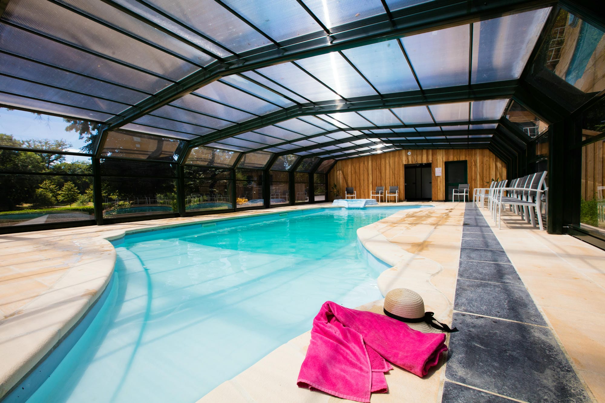 Serviette rose posée au bord de la piscine couverte et jacuzzi du Camping Le Verdoyer