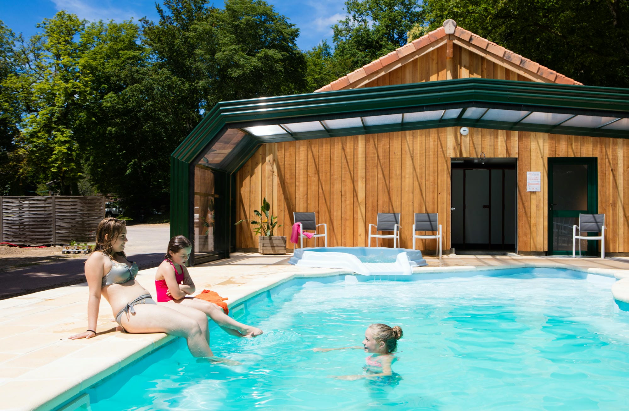 Deux femmes et un enfant se relaxant dans la piscine couverte avec jacuzzi au Verdoyer