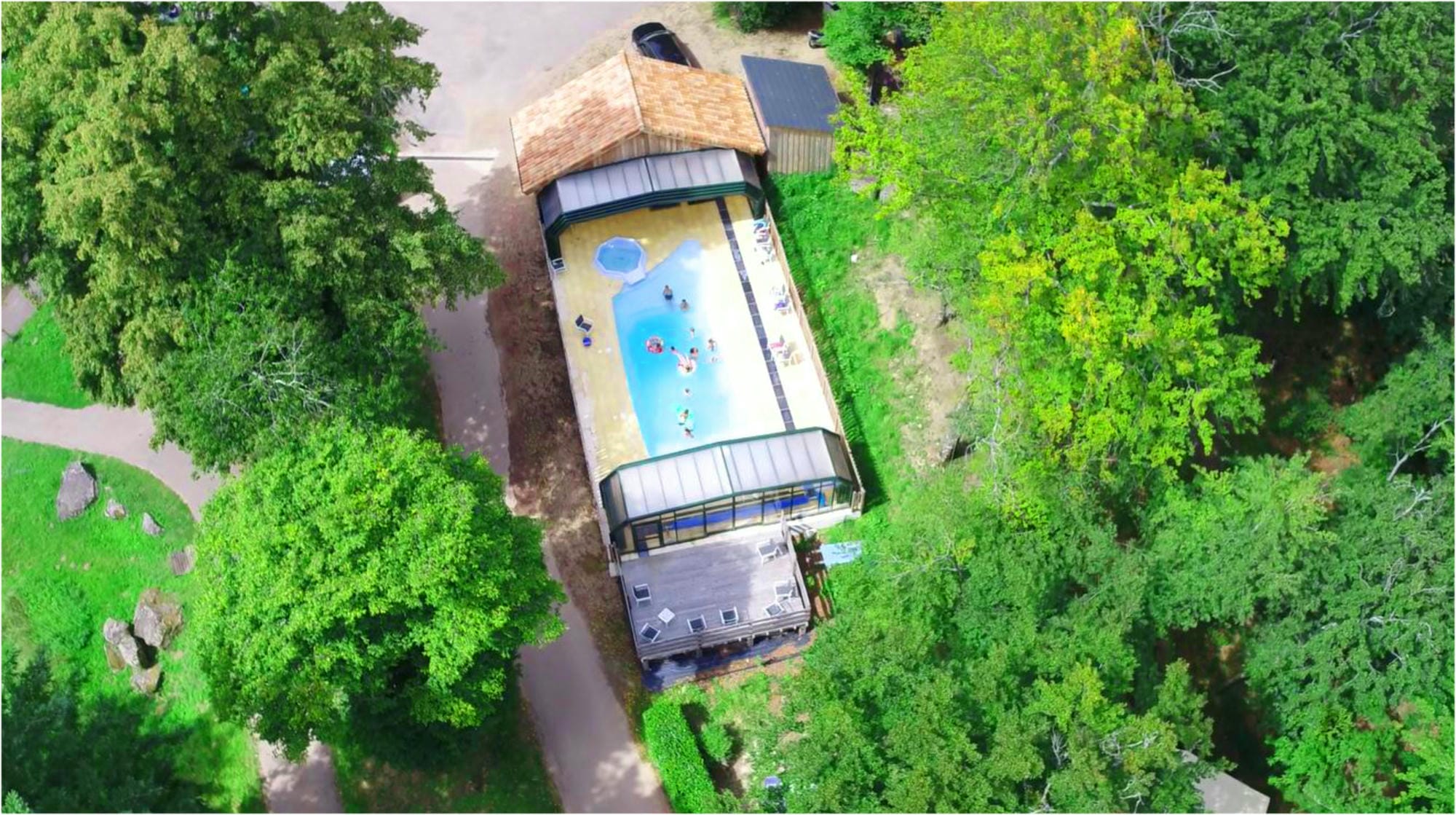 Vue aérienne de la piscine couverte du Camping Château le Verdoyer, nichée dans un espace boisé