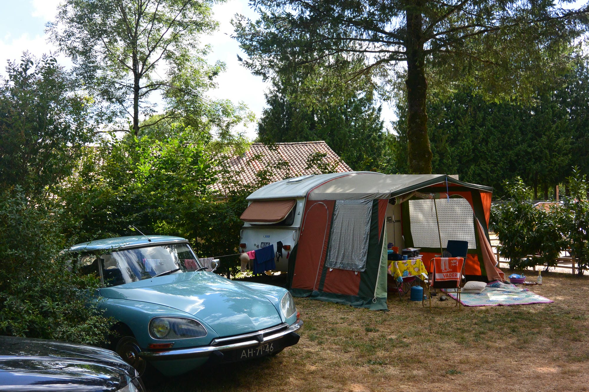 Citroën DS bleue garée devant une caravane rétro sur un emplacement de camping au Château le Verdoyer