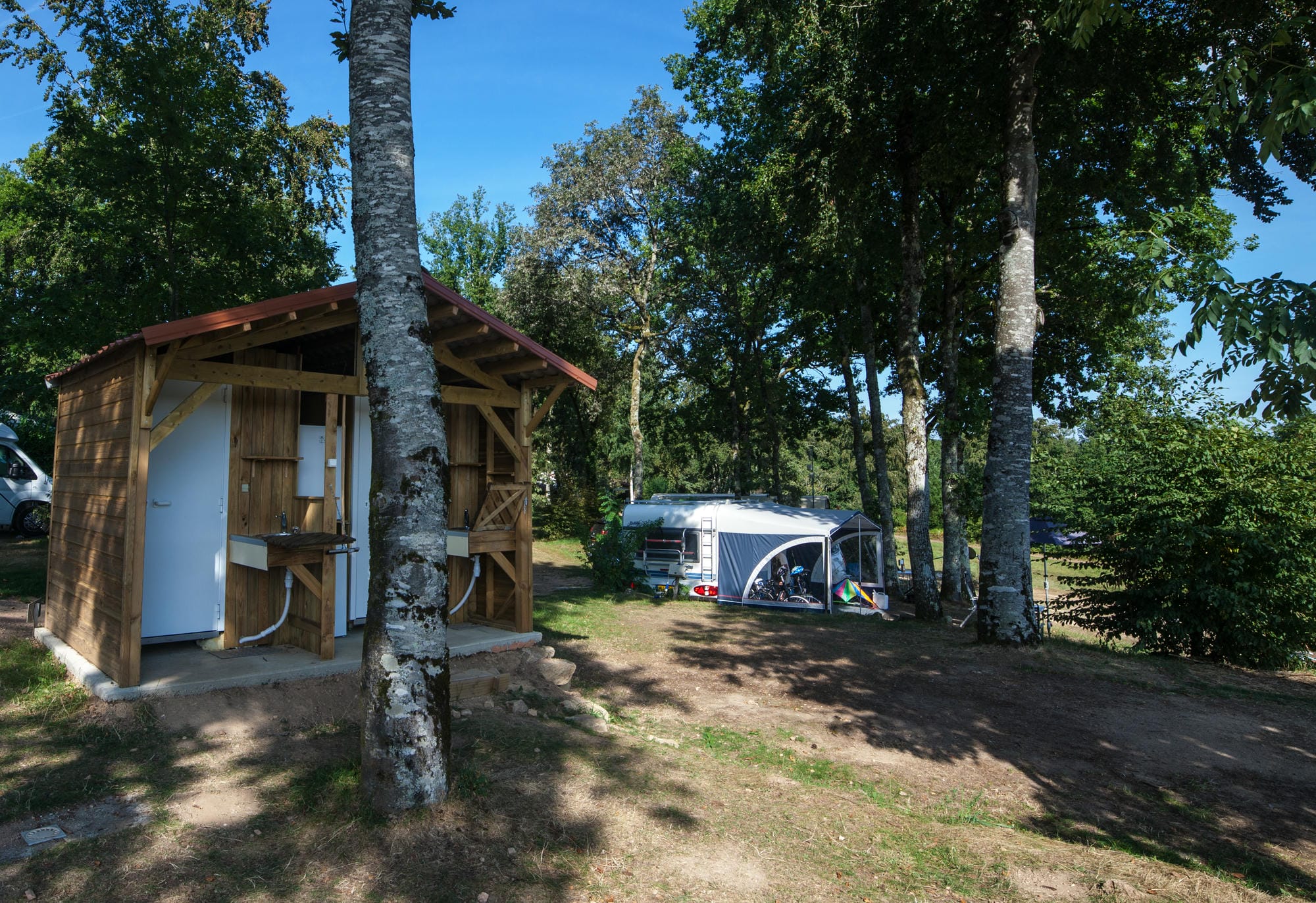 Petite cabane en bois sanitaire privé sur un emplacement de camping boisé au Verdoyer