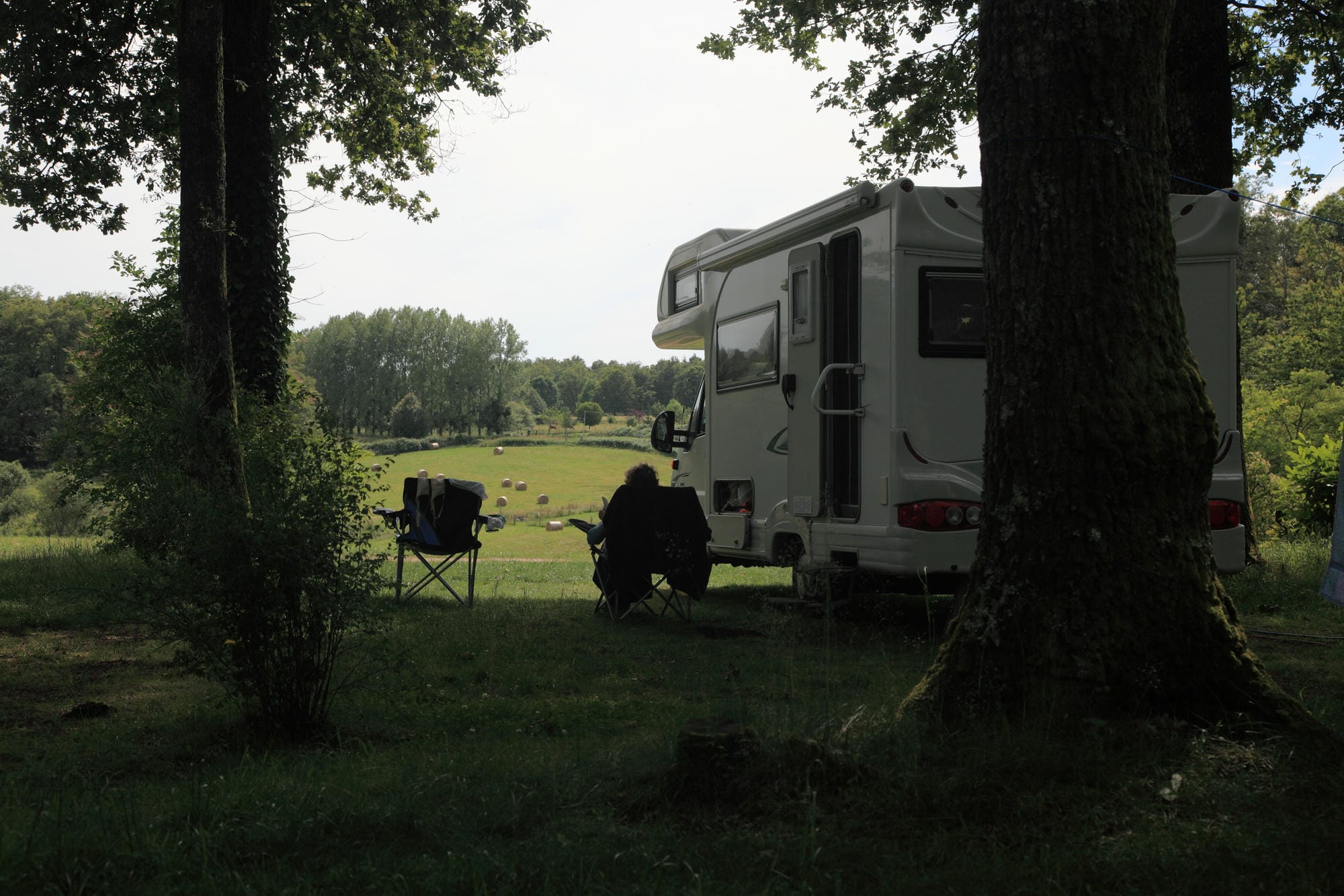 Homme profitant de son emplacement de camping assis à côté de son camping-car au Verdoyer