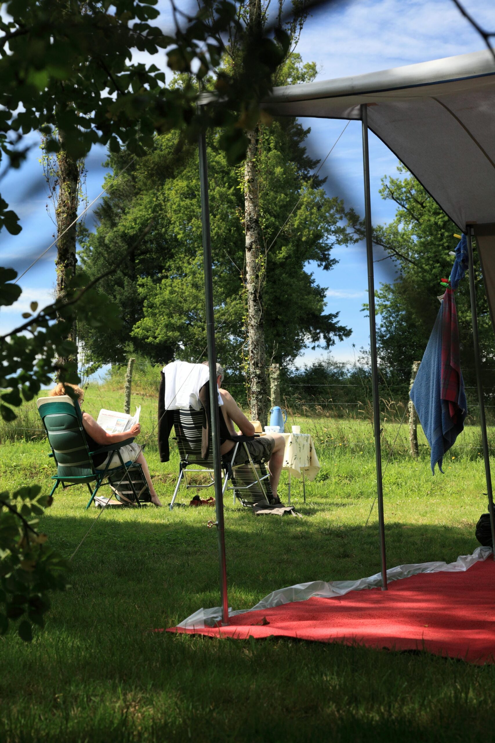 couple assis sur une chaise sous l'auvent de sa tente, camping confortable au Verdoyer