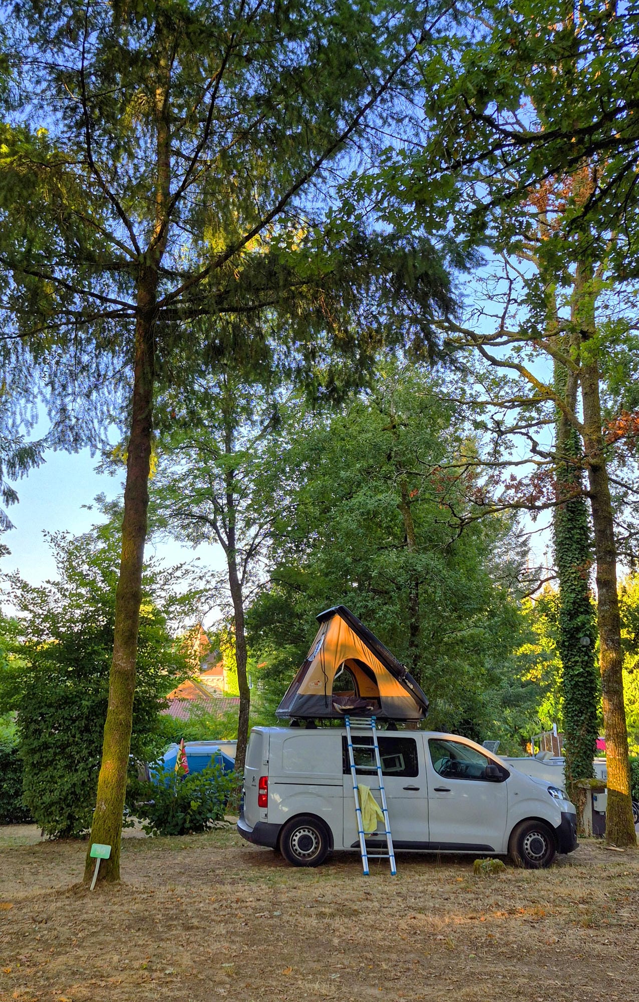 Emplacement de camping ombragé avec van aménagé et tente de toit au Château le Verdoyer