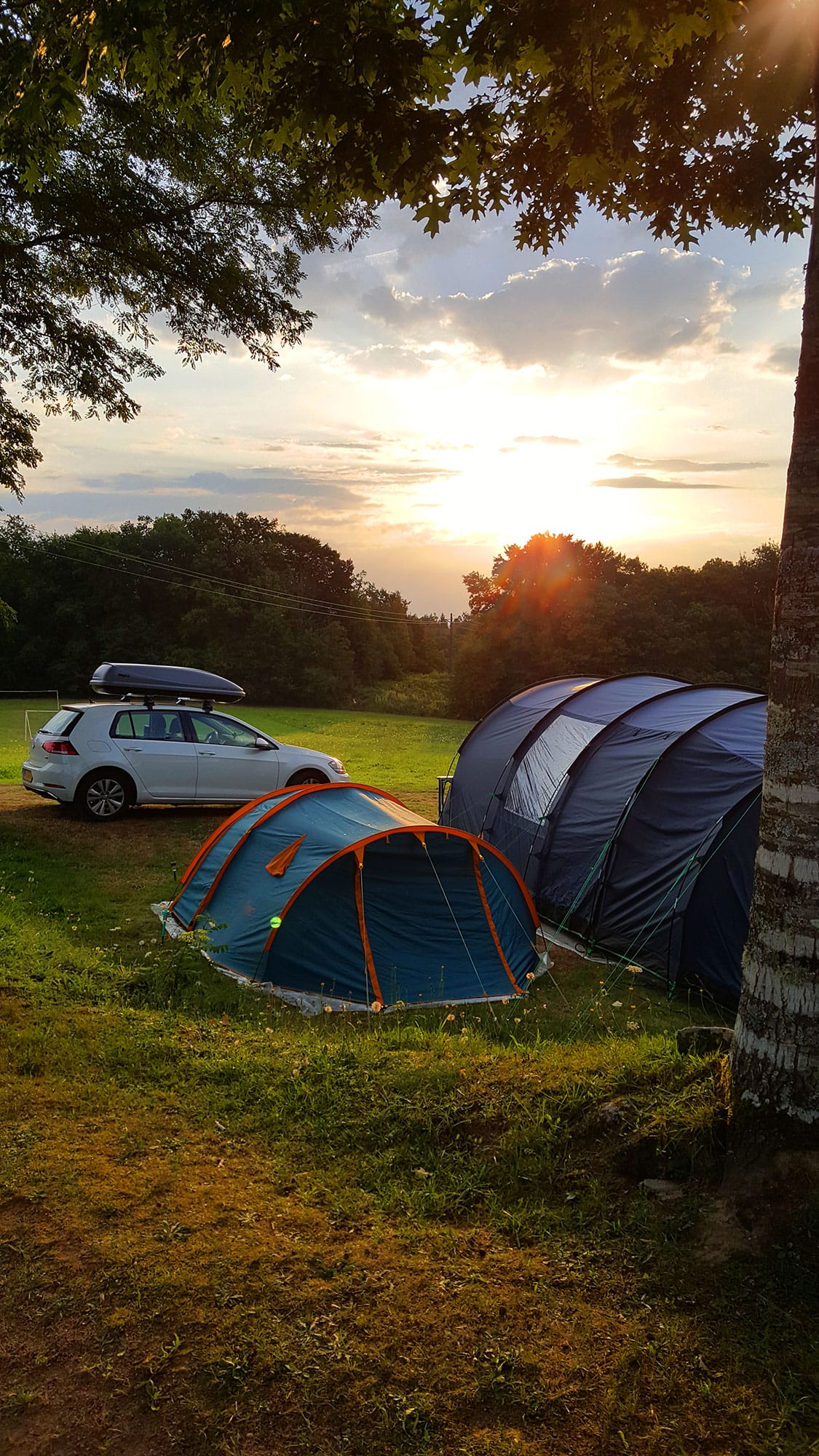 Tentes plantées dans un champ avec une voiture garée à proximité, Camping Le Verdoyer