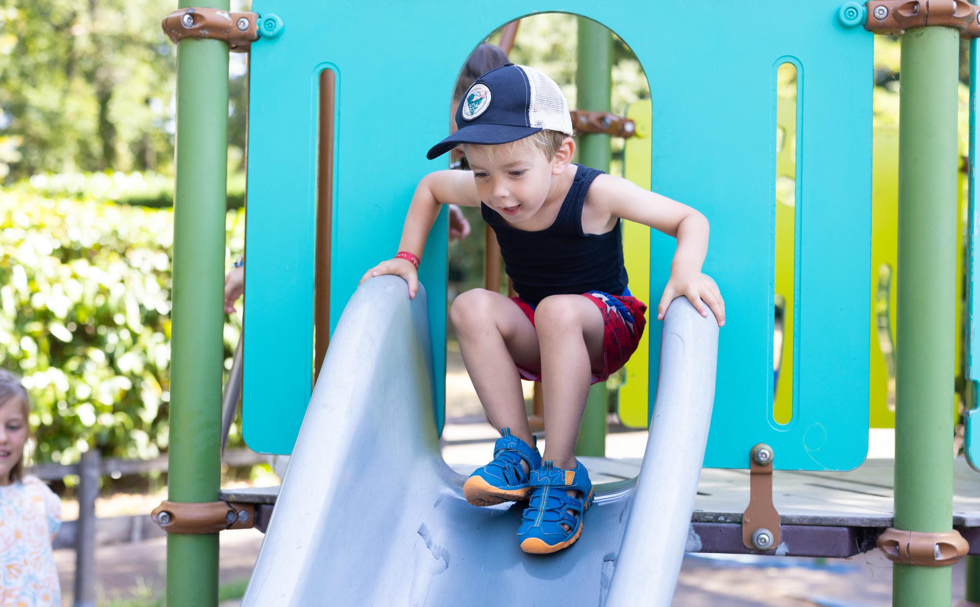 Jeune garçon s'amusant sur le toboggan de l'aire de jeux au camping Château le Verdoyer