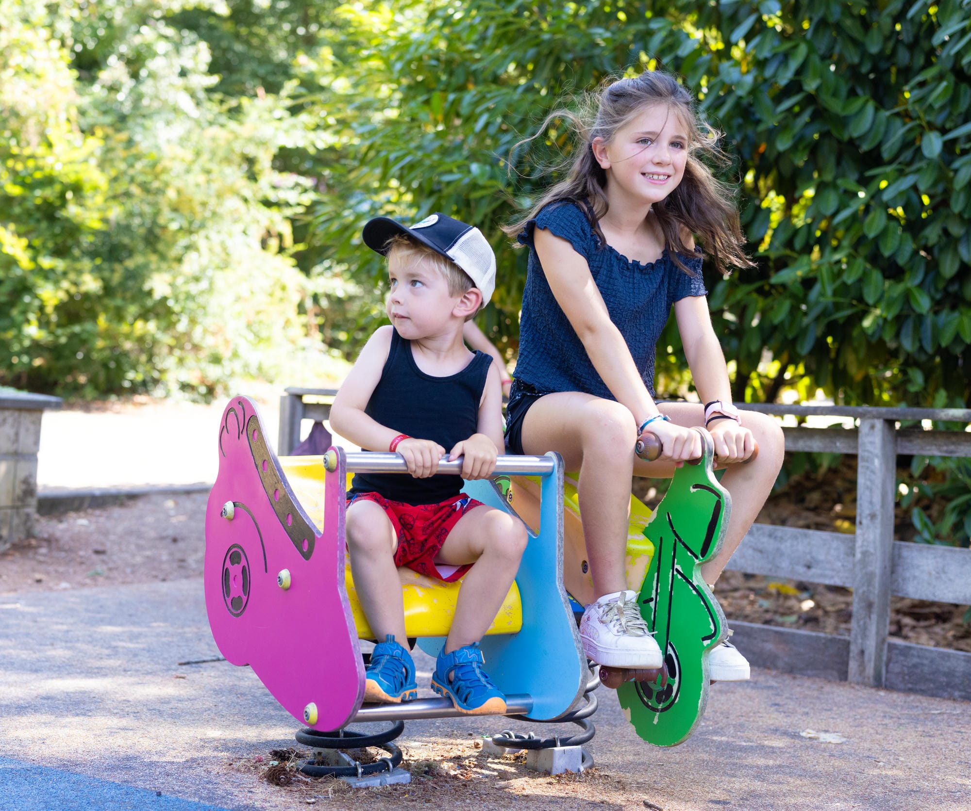 Enfants profitant de la balançoire à ressort sur l'aire de jeux familiale du Château le Verdoyer