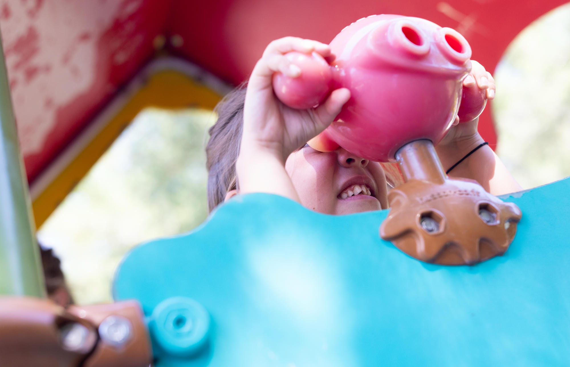 Enfant joyeux jouant sur les équipements colorés de l'aire de jeux du Château le Verdoyer