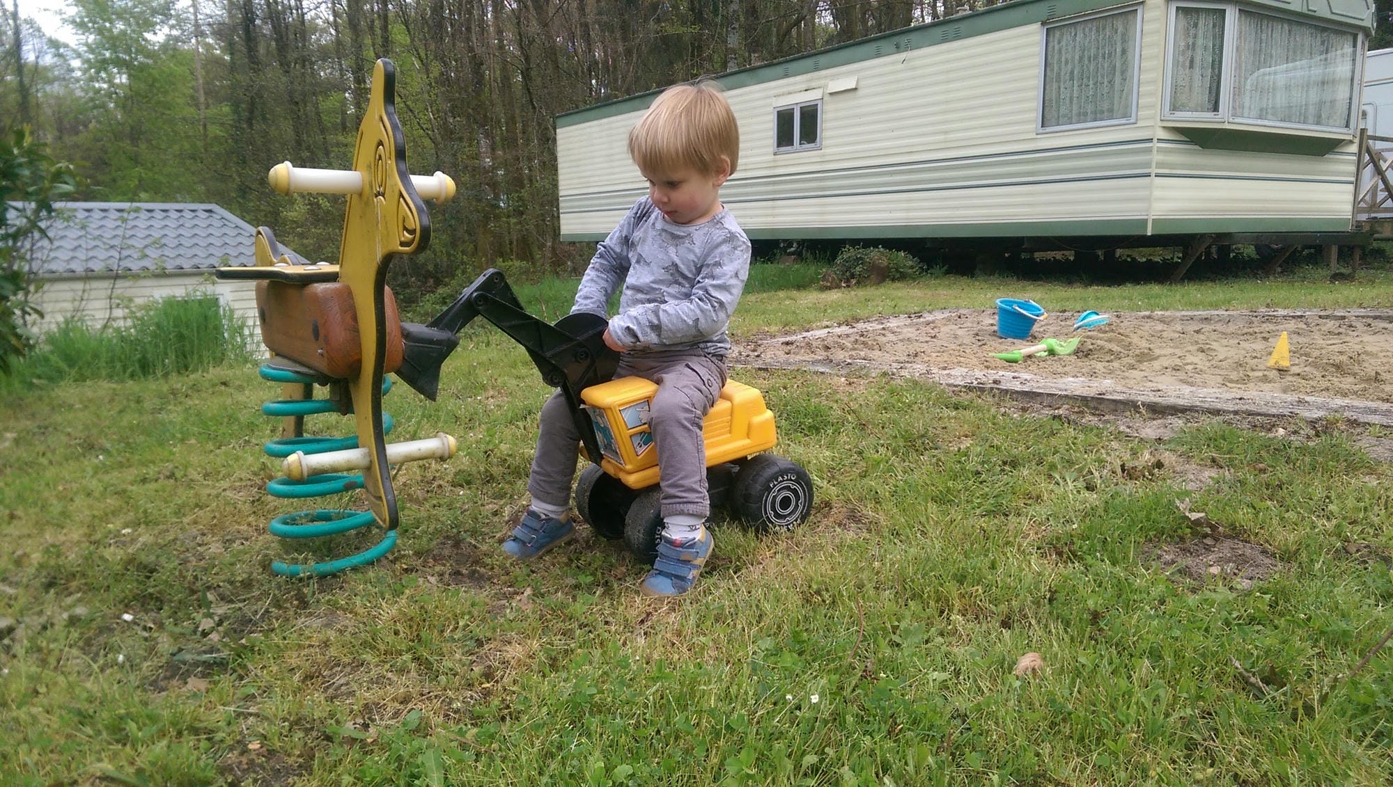 Petit enfant assis sur un camion jouet, aire de jeux pour les plus jeunes au Verdoyer