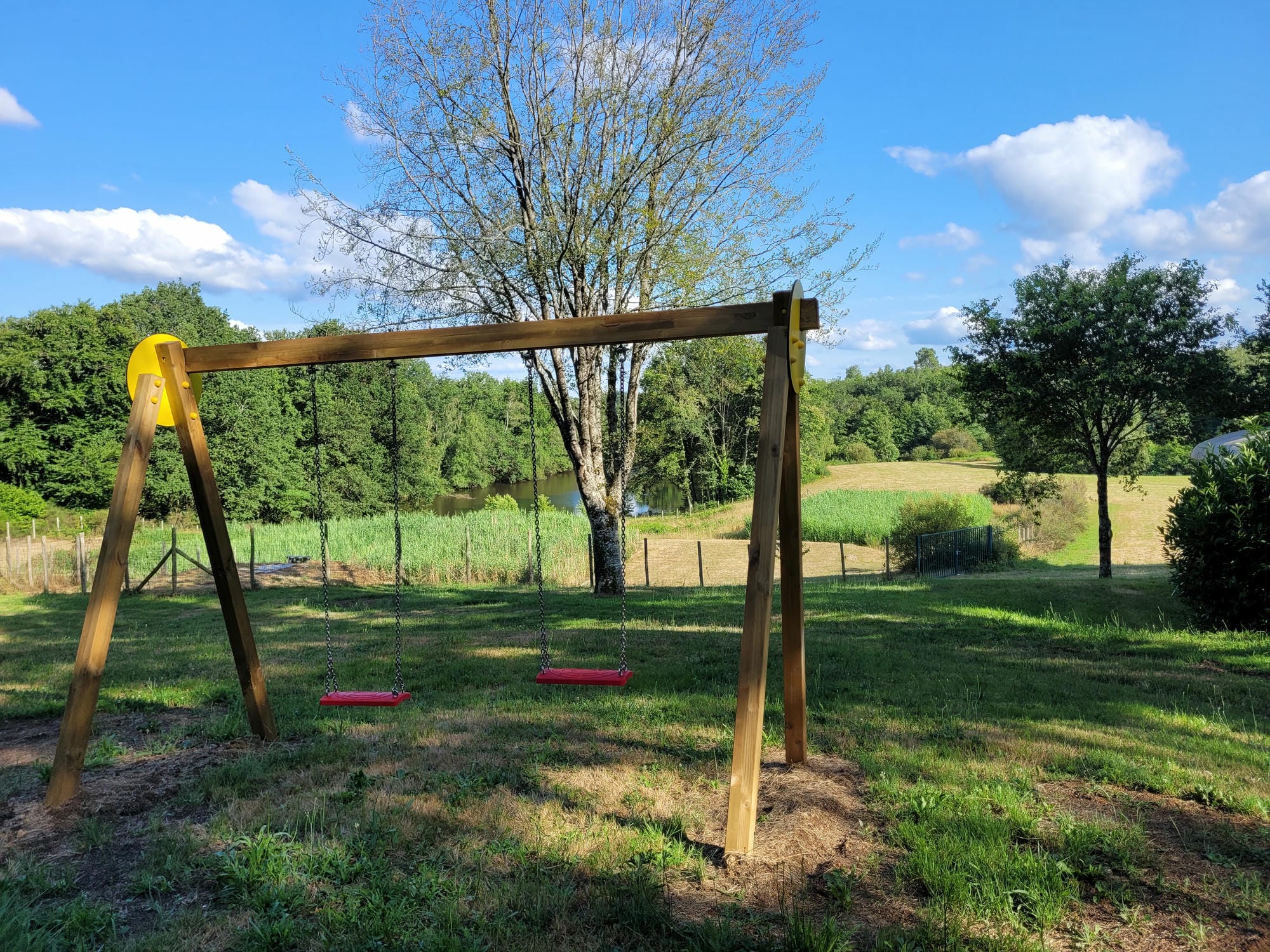 Balançoires sur la pelouse de l'aire de jeux du Camping Château le Verdoyer