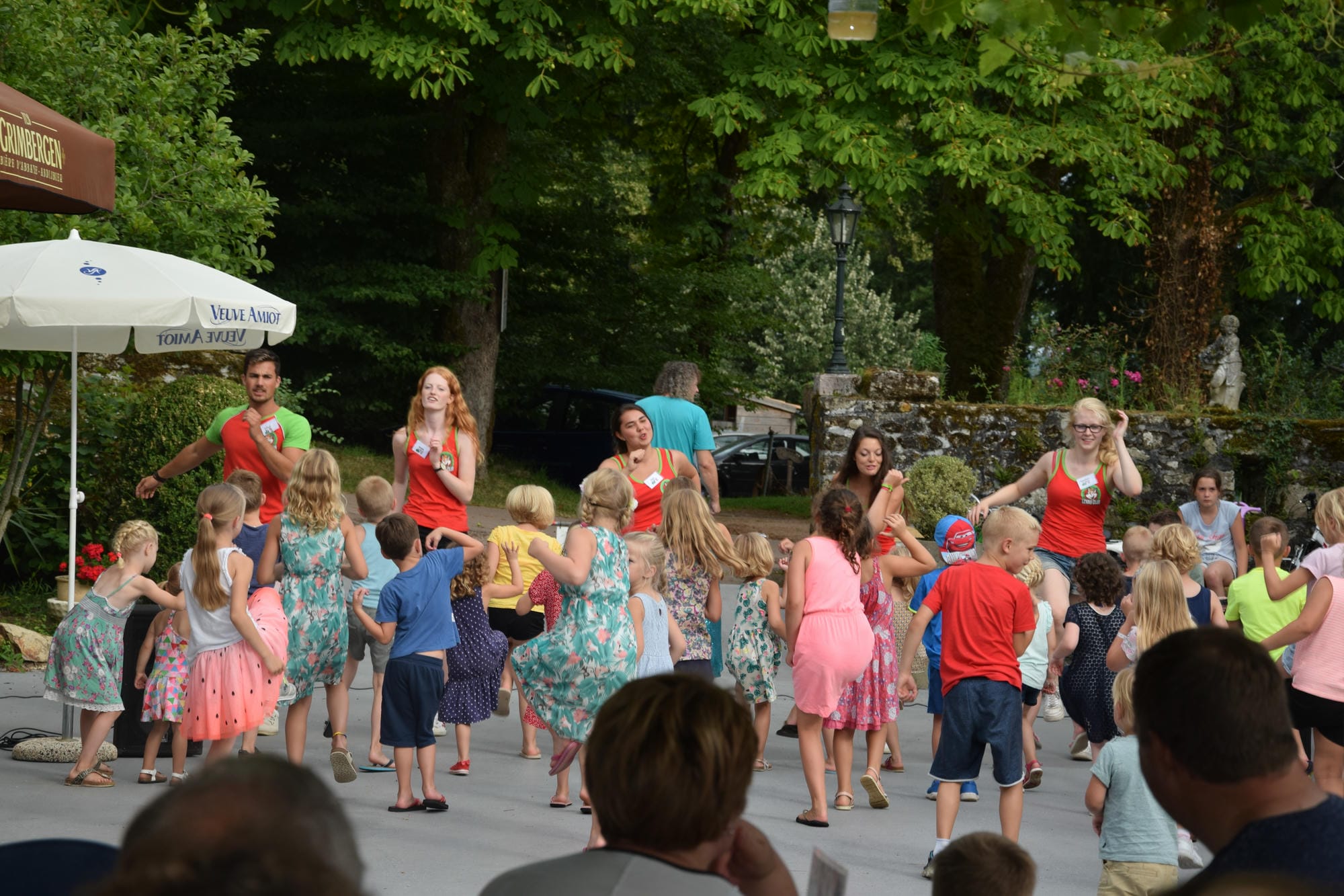 Grand cercle d'enfants et d'adultes participant à une animation de rue au Camping Le Verdoyer