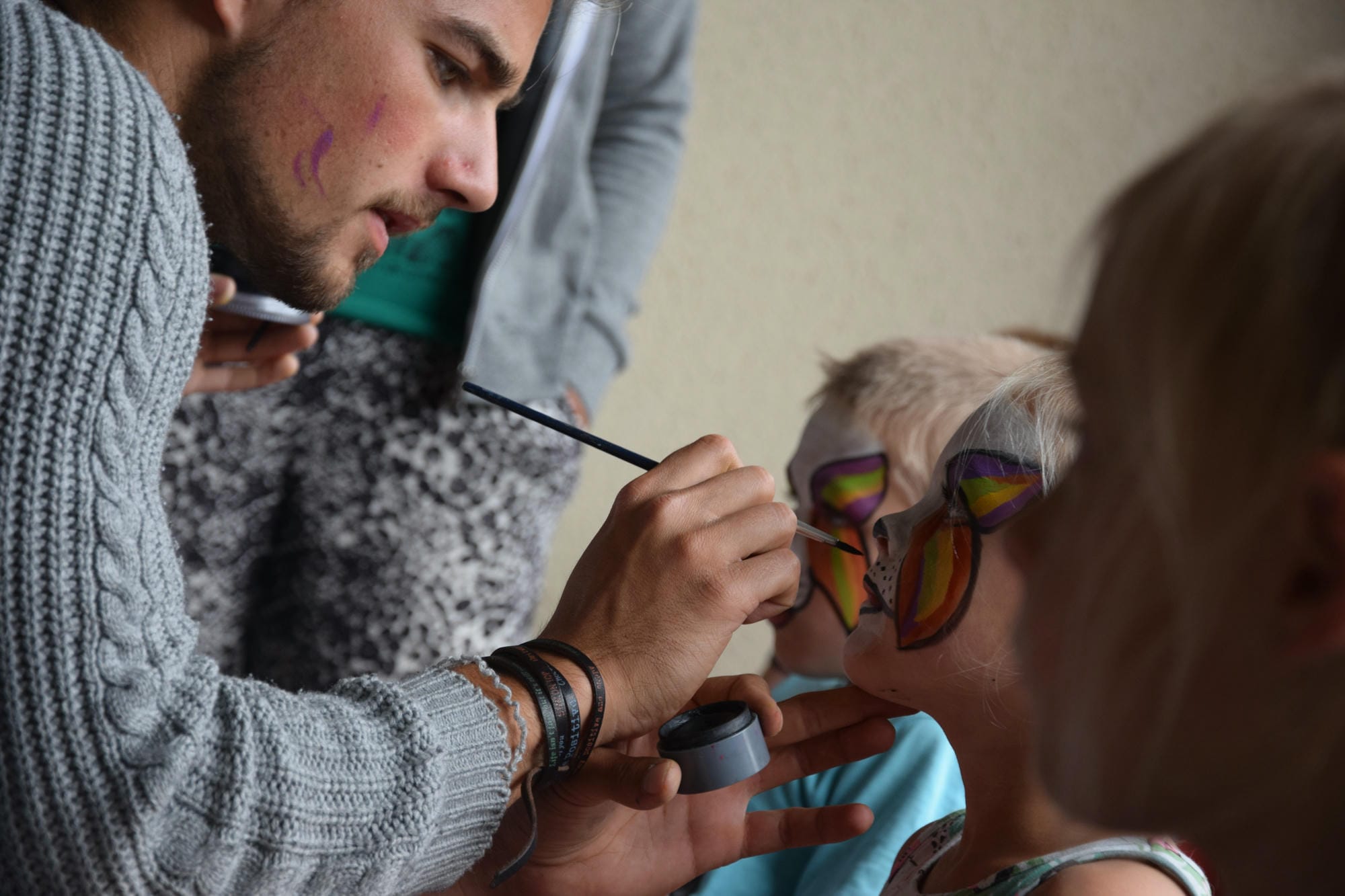 Animateur maquillant le visage d'un enfant avec des couleurs vives, club Lenny au Verdoyer