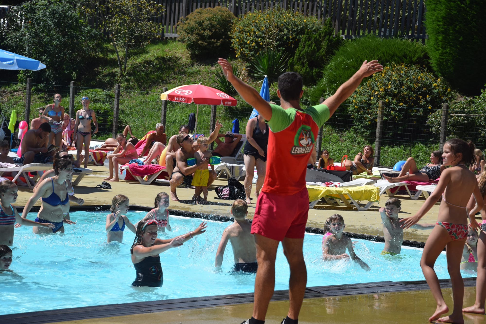 Jeux dans la piscine avec un homme sautant, ambiance festive au Camping Château le Verdoyer