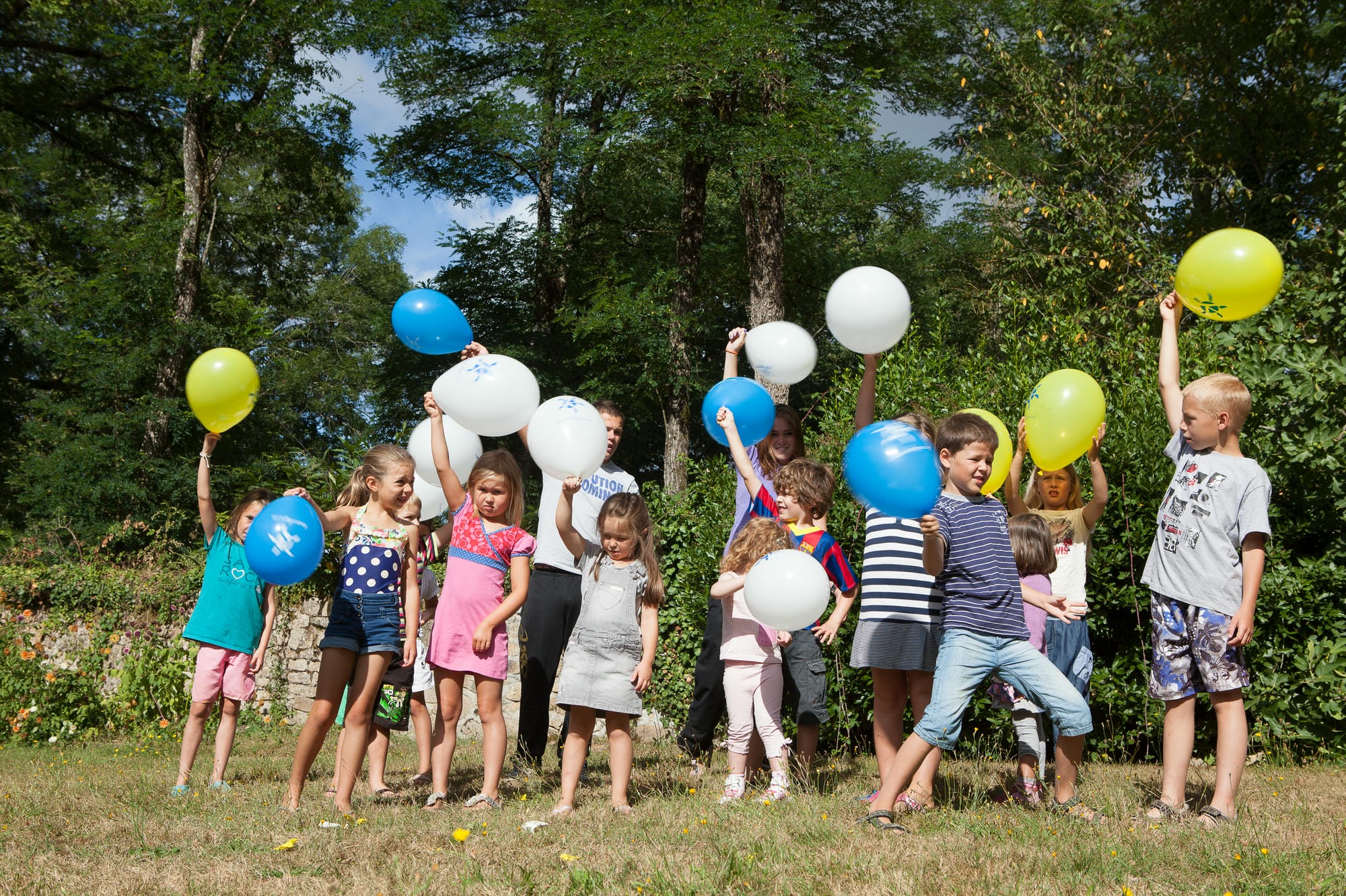 Groupe d'enfants tenant des ballons dans un champ, fête au club Lenny du Château le Verdoyer