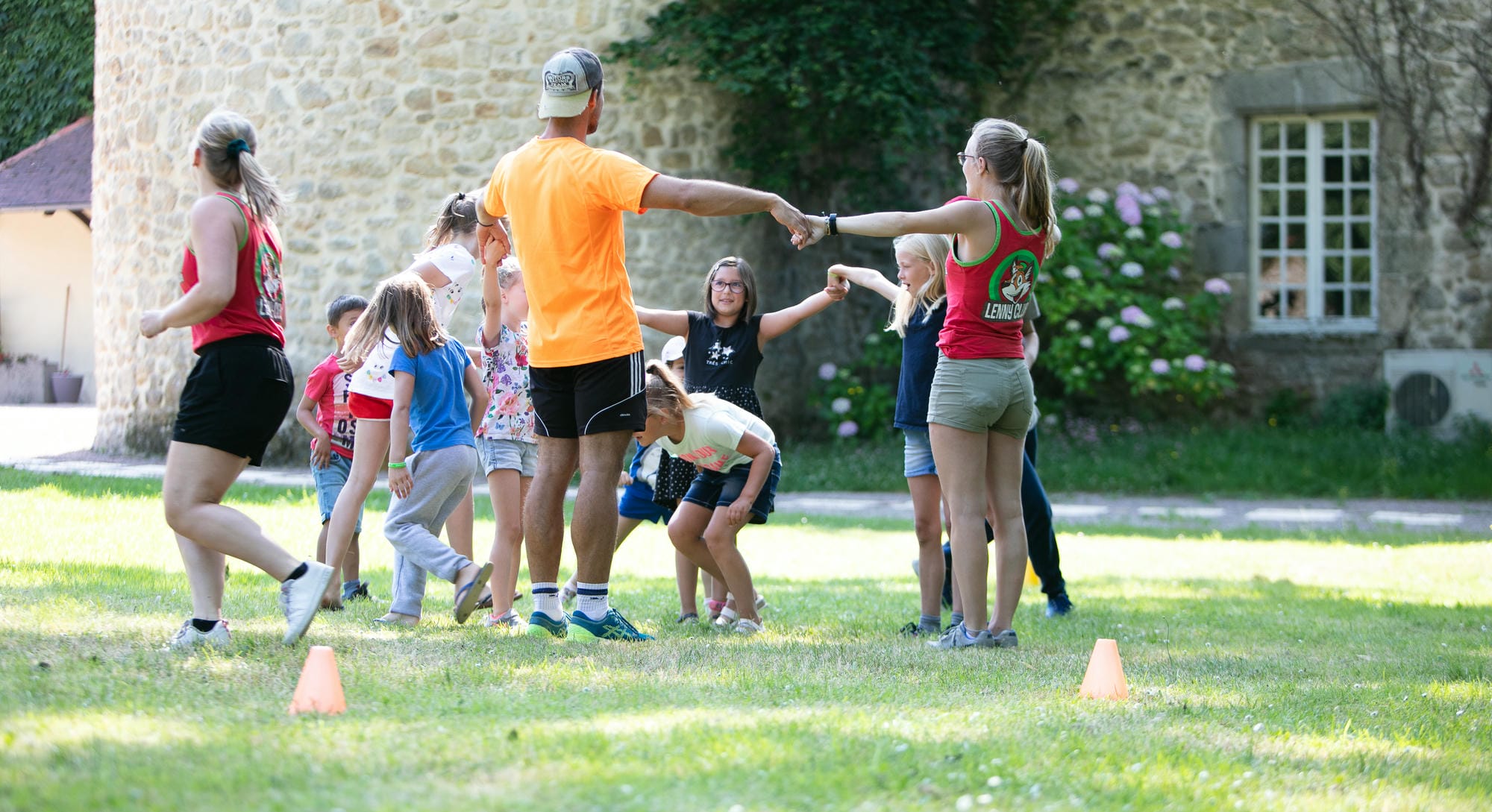 Enfants et animateurs jouant sur la prairie, animation au Camping Château le Verdoyer