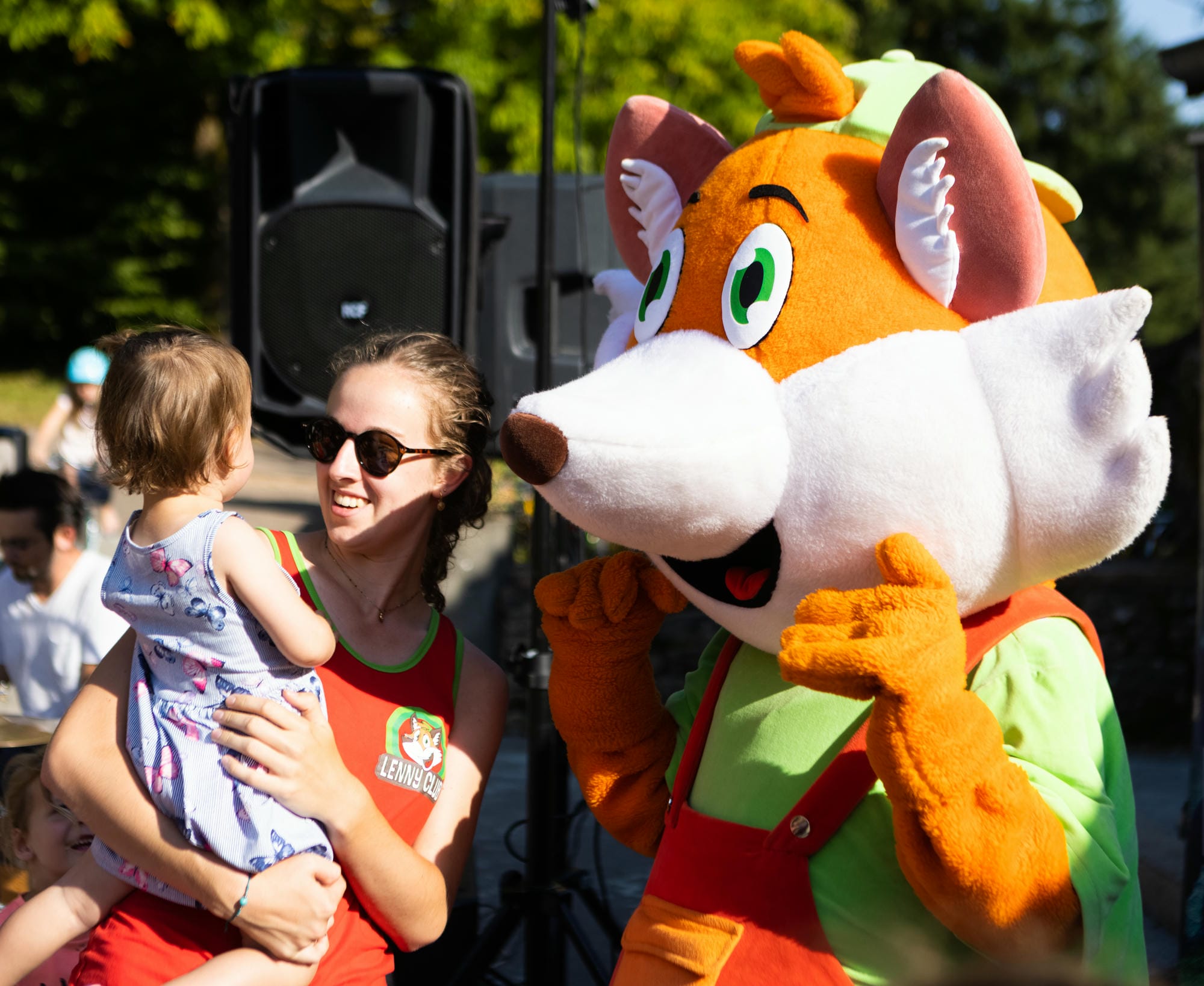 Animatrice avec un enfant dans les bras et Lenny, la mascotte du club enfants au Château le Verdoyer