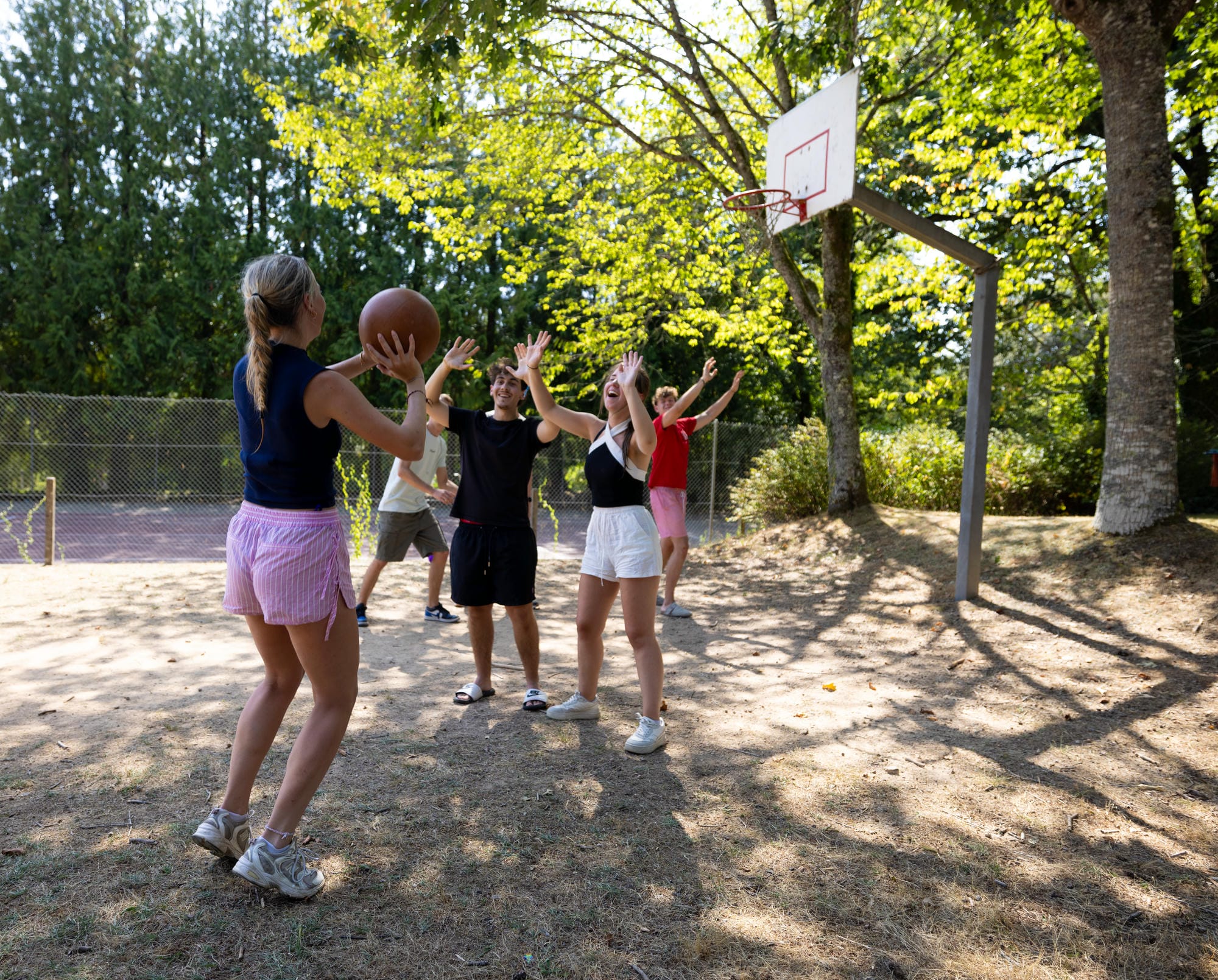 Enfants jouant au basketball sur le terrain de sport du camping Château le Verdoyer