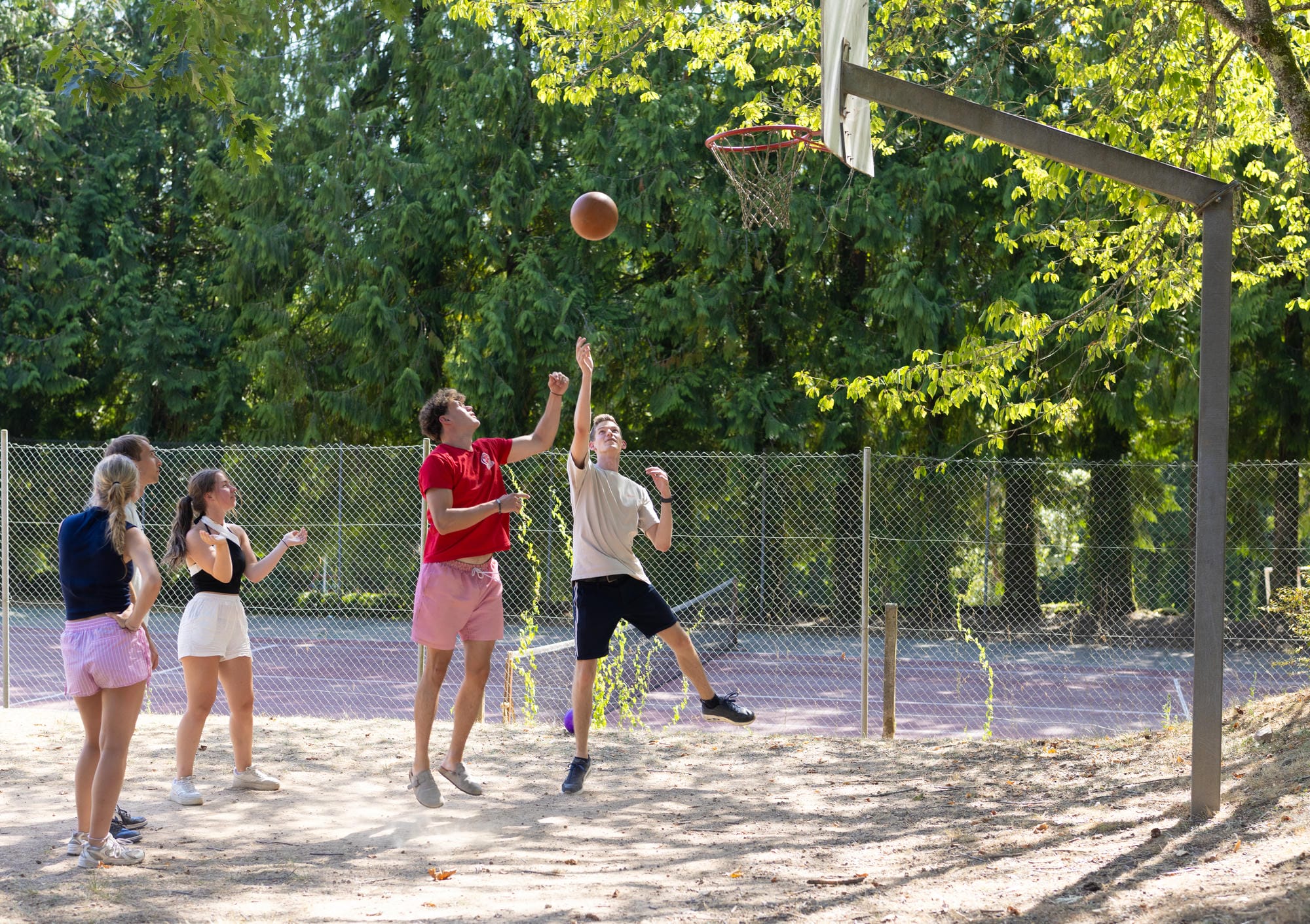 Jeunes jouant au basketball sur le terrain extérieur du camping Château le Verdoyer