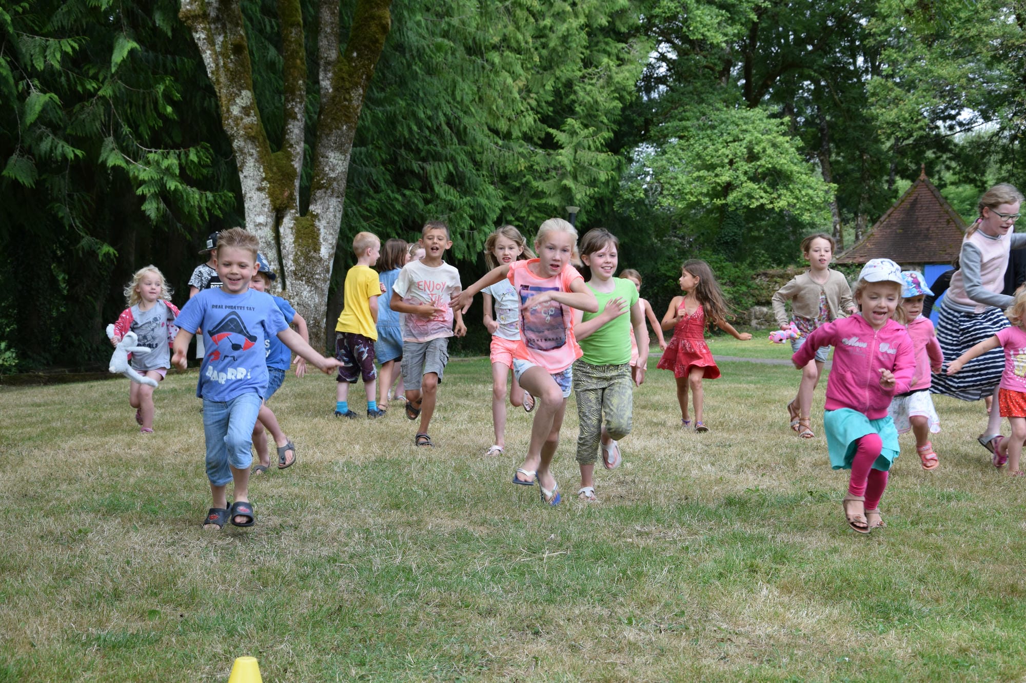 Nombreux enfants courant joyeusement dans un champ, jeux au club Lenny du Château le Verdoyer