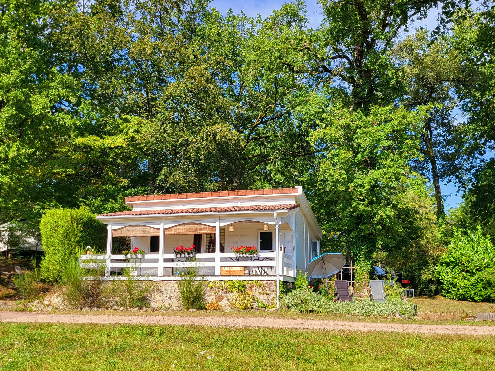 Chalet en bois blanc avec toit rouge et porche, hébergement de charme au Château le Verdoyer