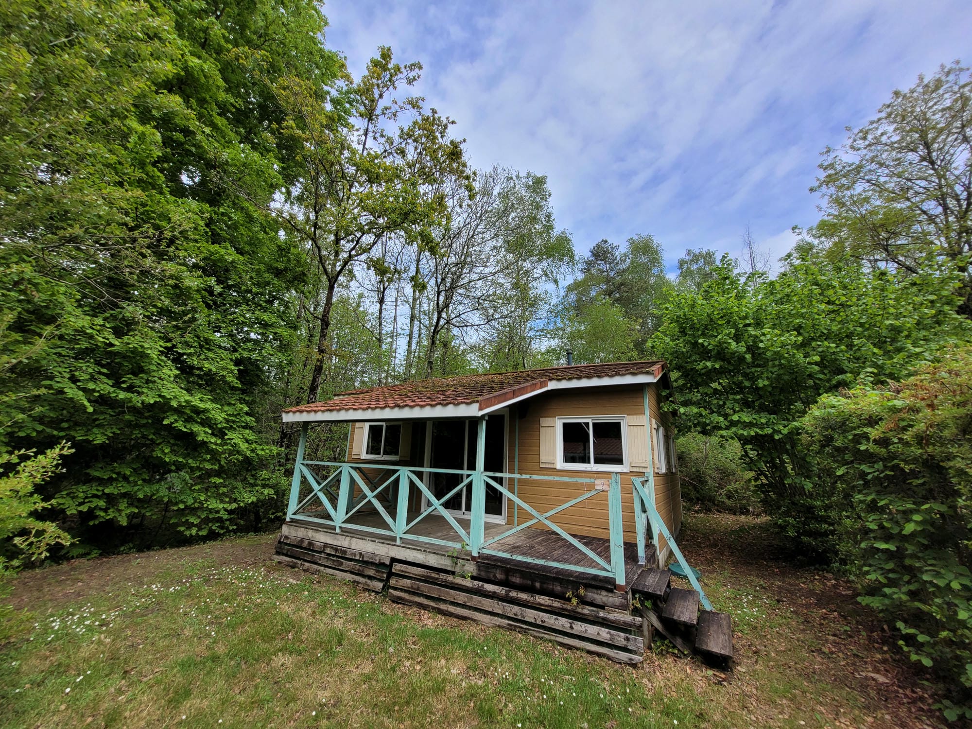 Chalet en bois avec porche et balustrade, hébergement au Camping Château le Verdoyer
