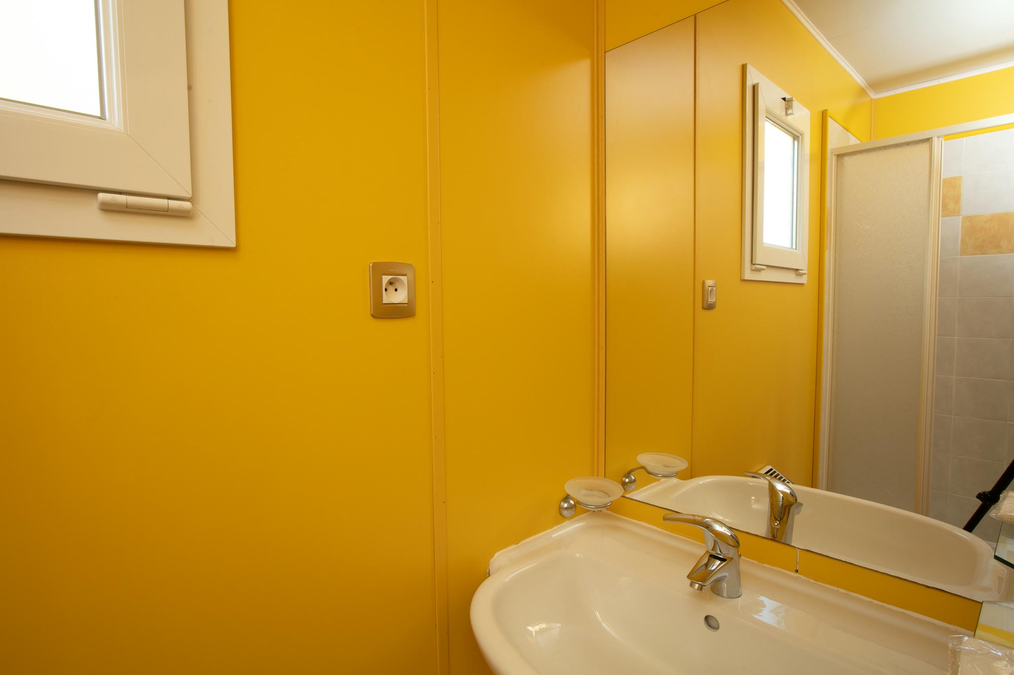 Salle de bain avec lavabo et douche dans un chalet en bois, confort au Camping Le Verdoyer
