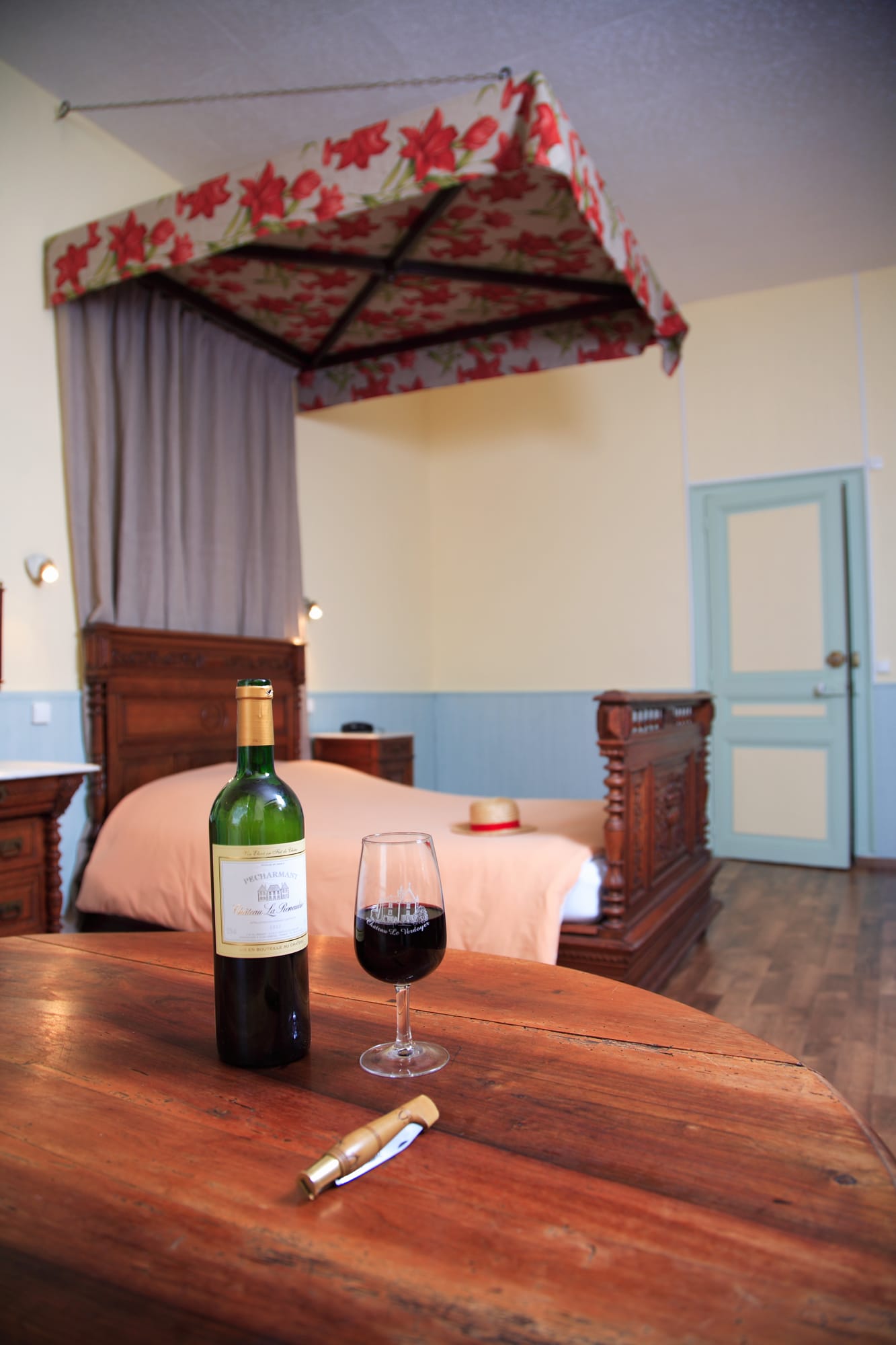 Bouteille de vin et verre prêts à la dégustation dans la chambre 11 du Château le Verdoyer