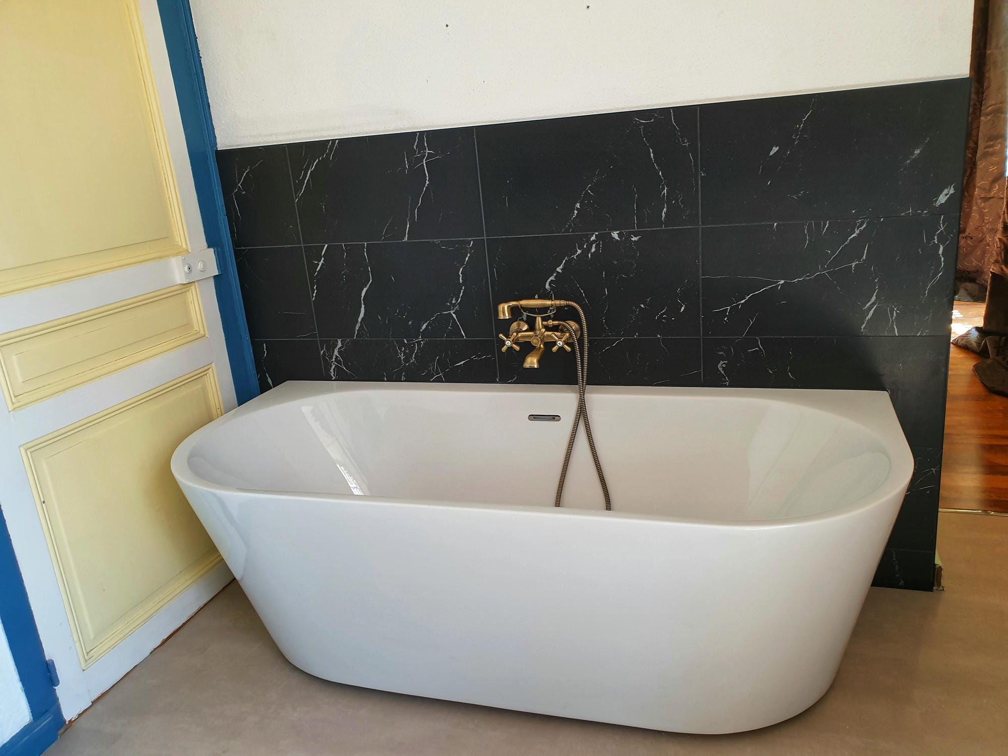 Baignoire dans la salle de bain de la chambre 11 au Château, mur carrelé noir et blanc