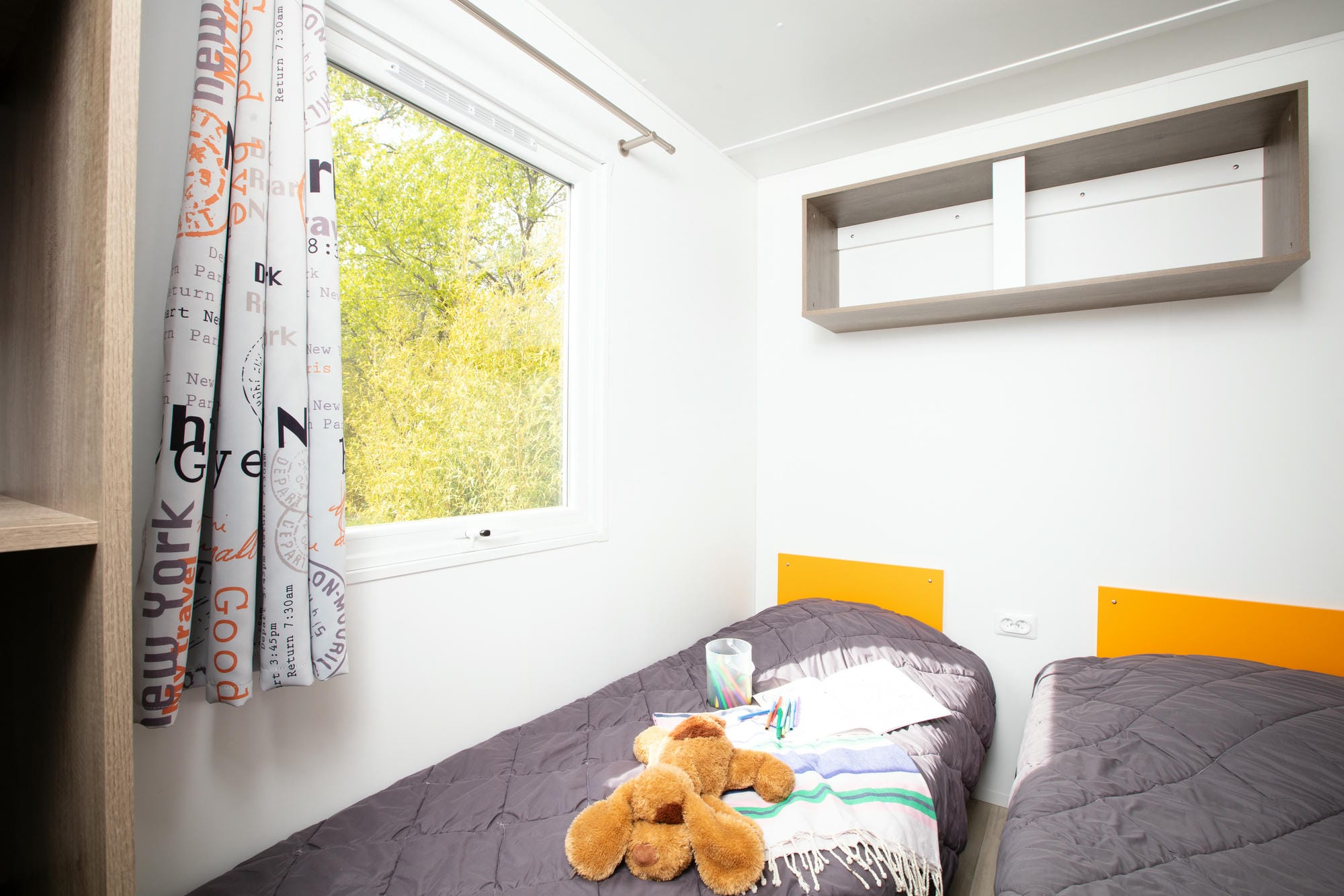 Ours en peluche sur un lit dans une chambre de mobil-home 3 chambres au Verdoyer