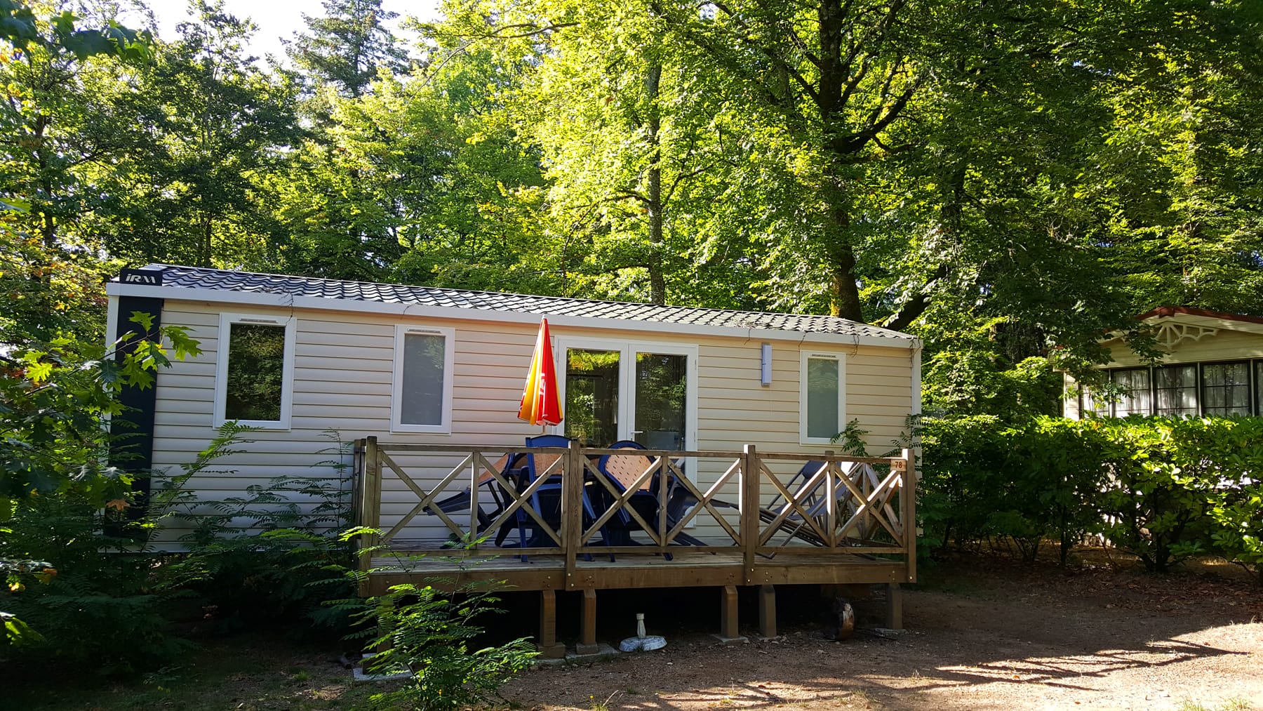 Mobil-home 3 chambres avec terrasse et parasol rouge, confort familial au Camping Le Verdoyer