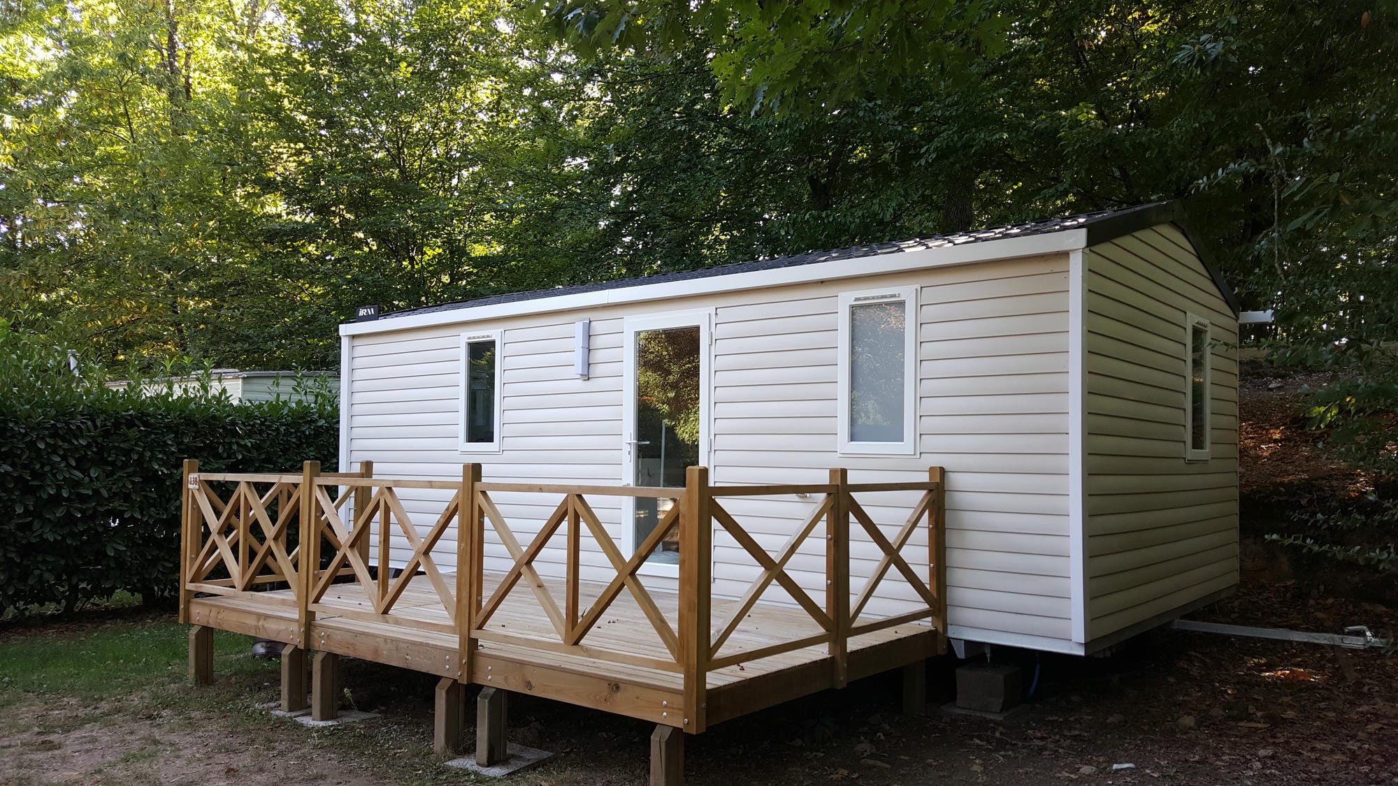Mobil-home de luxe blanc avec terrasse en bois dans le jardin, hébergement de qualité au Verdoyer
