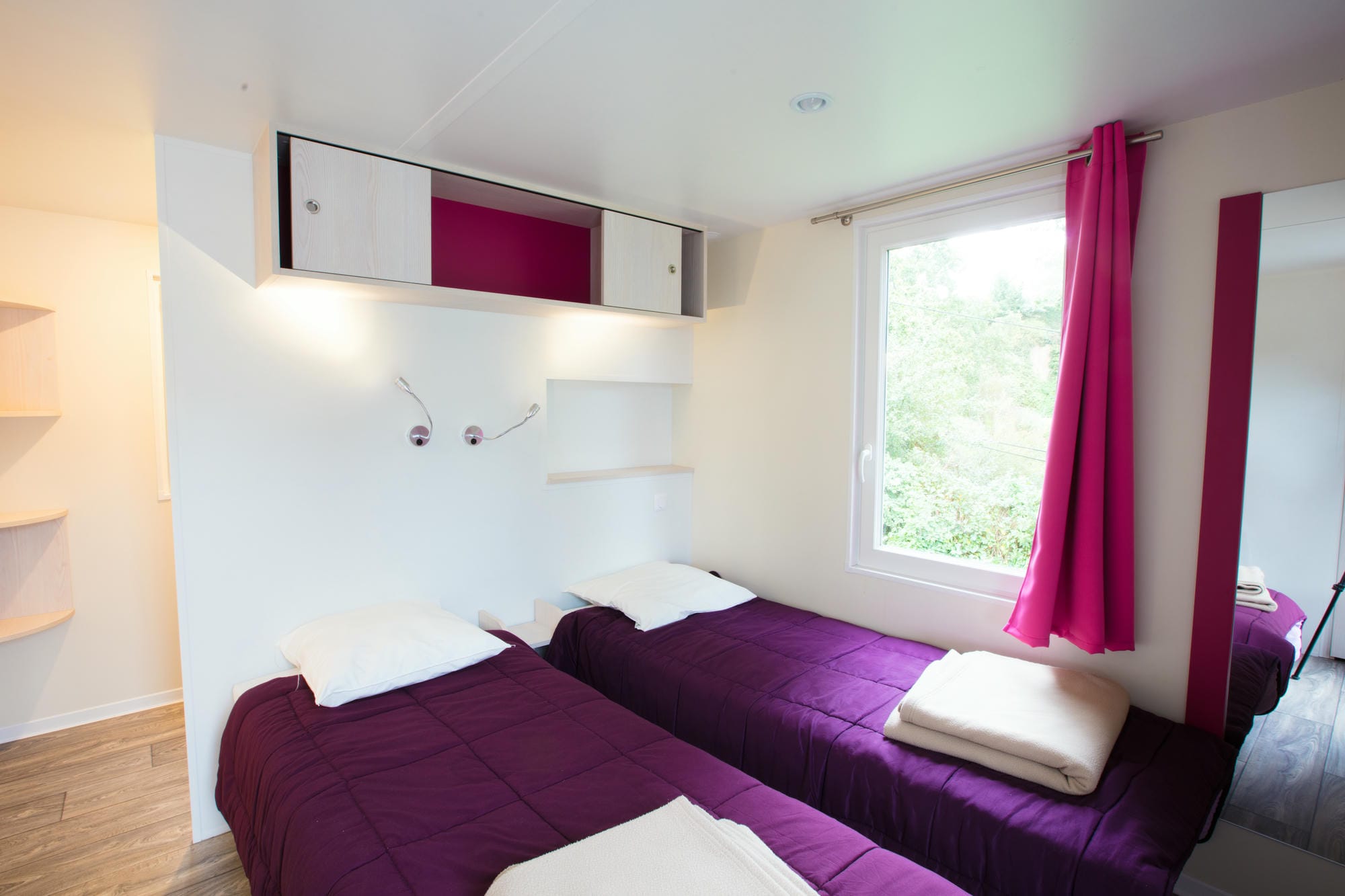 Couvre-lit violet sur un lit dans un mobil-home de luxe au Camping Château le Verdoyer
