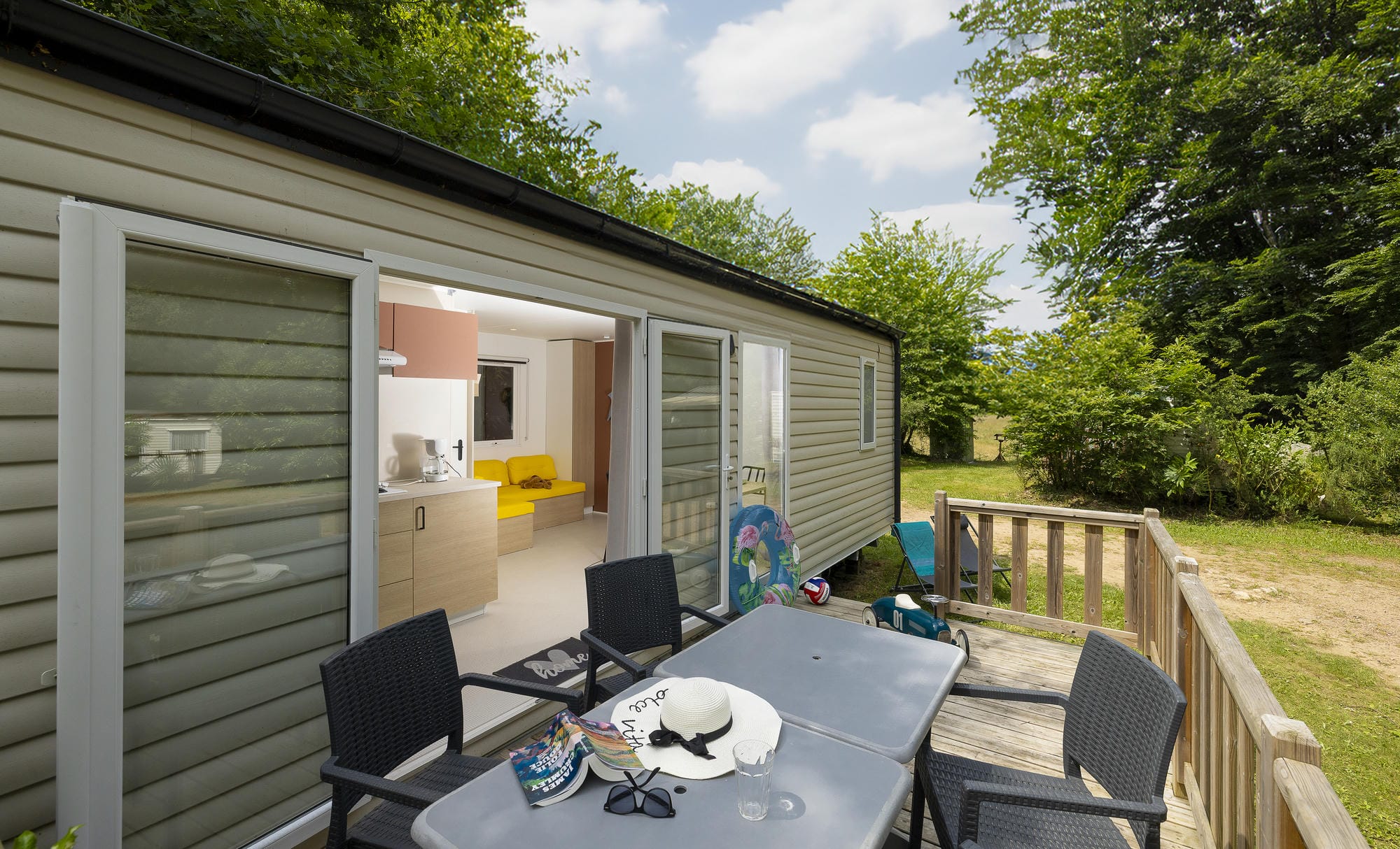Terrasse meublée du mobil-home luxe avec salon de jardin et vue sur l'intérieur au Château le Verdoyer