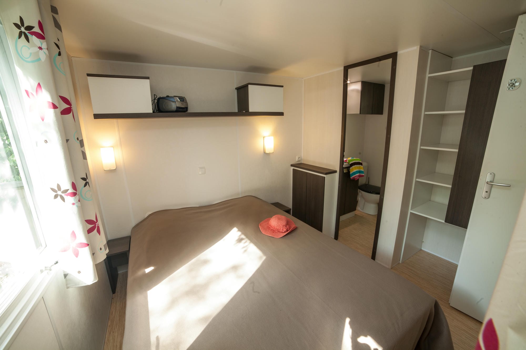 Lit avec couverture marron dans un mobil-home au Camping Château le Verdoyer