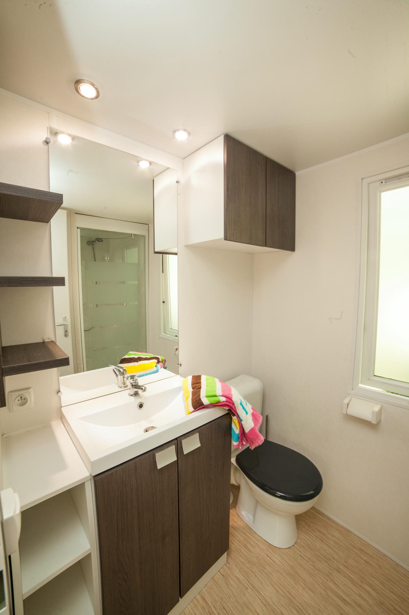 Salle de bain avec WC, lavabo et miroir dans un mobil-home du Château le Verdoyer
