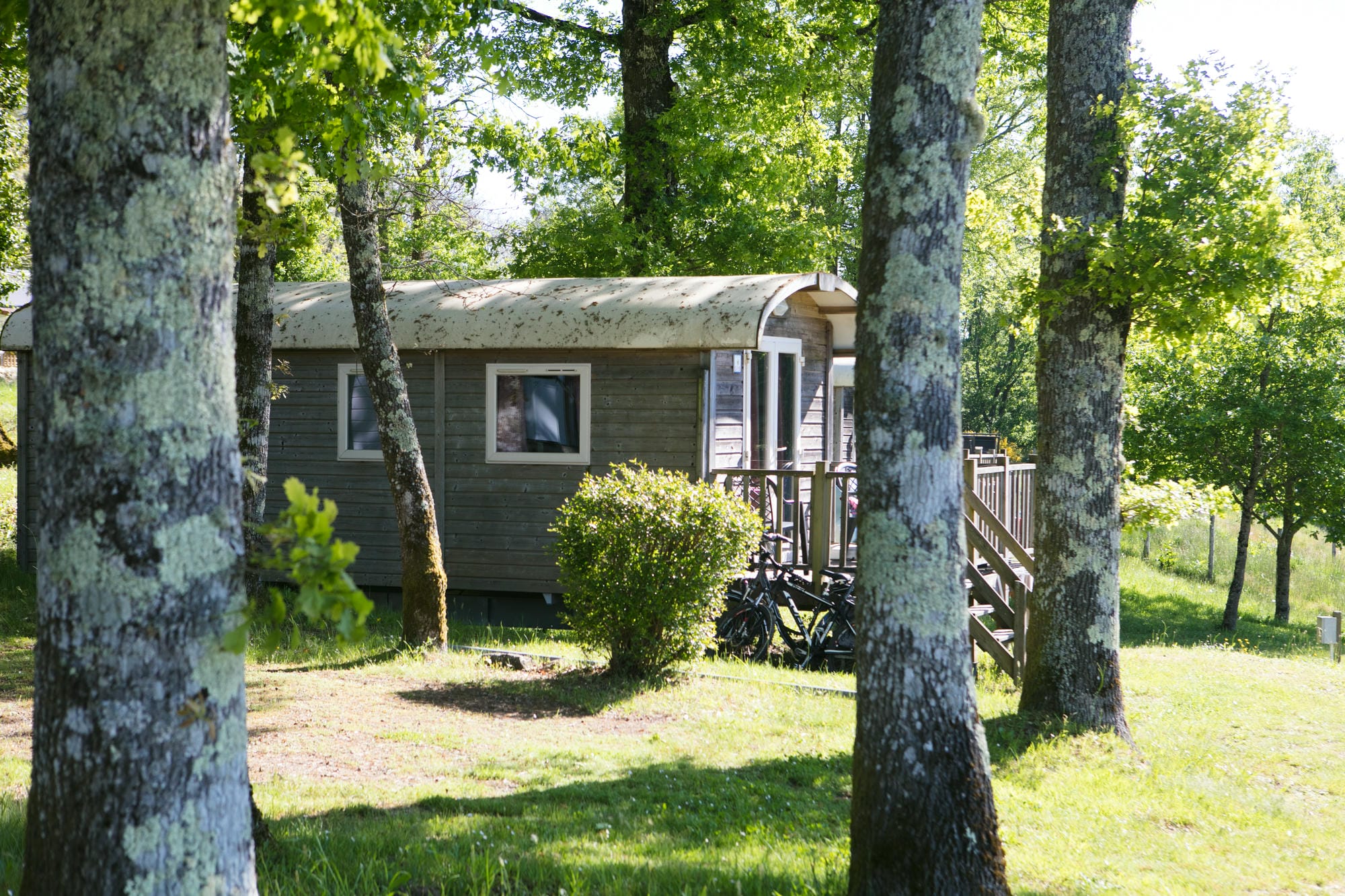 Roulotte de charme en bois avec vélo garé devant, hébergement insolite au Camping Le Verdoyer